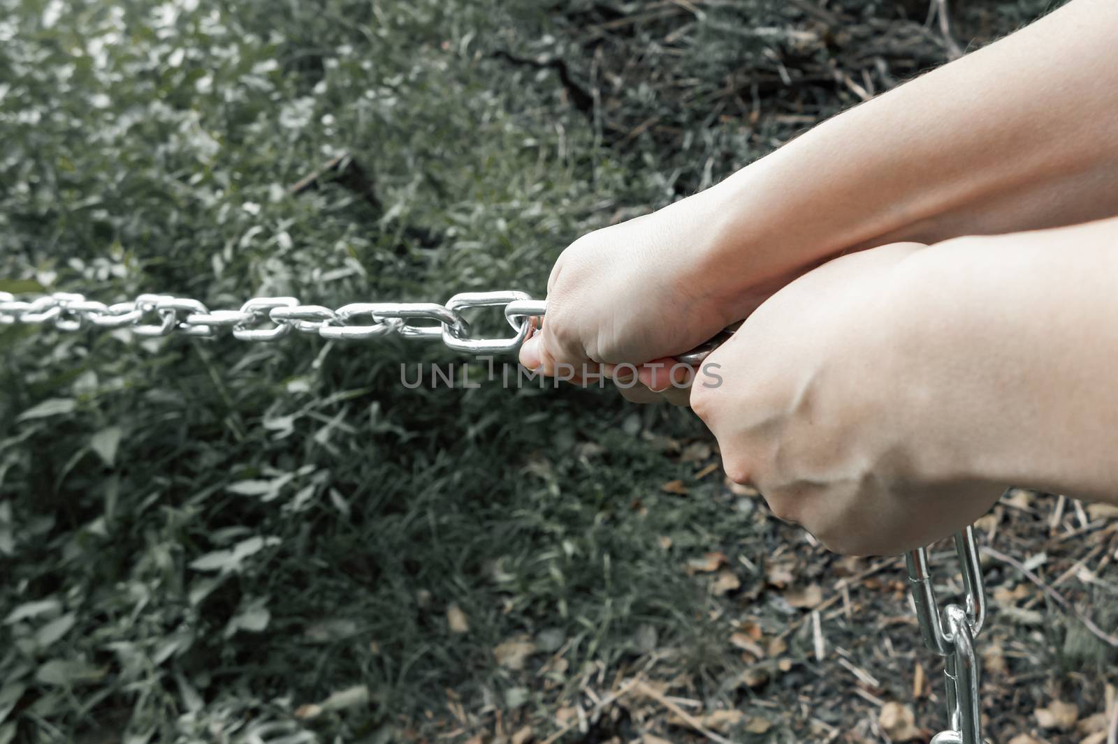 Female hands pulling a thick metal chain - the concept of hard work, unbearable burden.