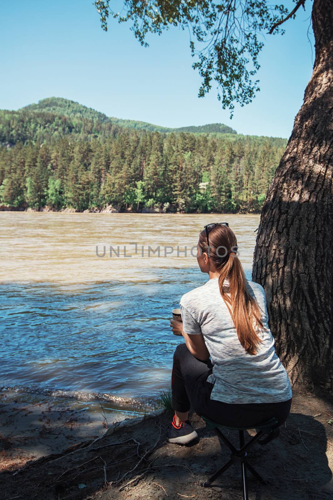 Woman having rest on river coast at the Altai mountain