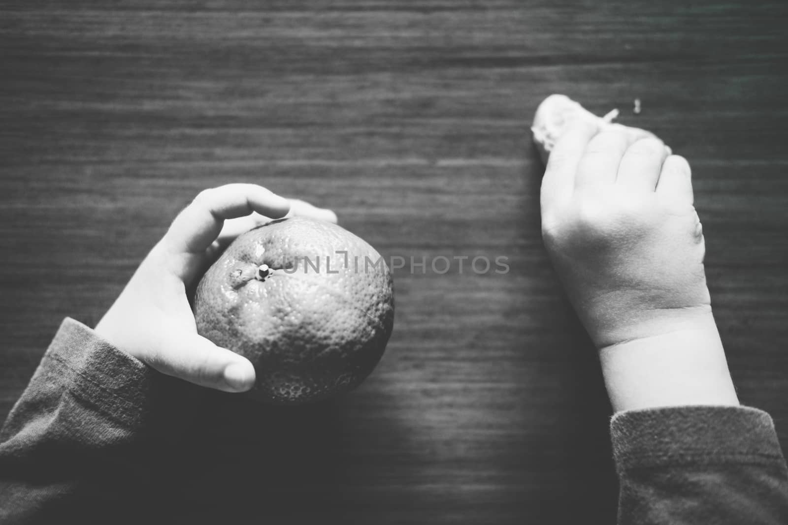 Little baby holding a tangerine in one hand and a slice in the other by mikelju