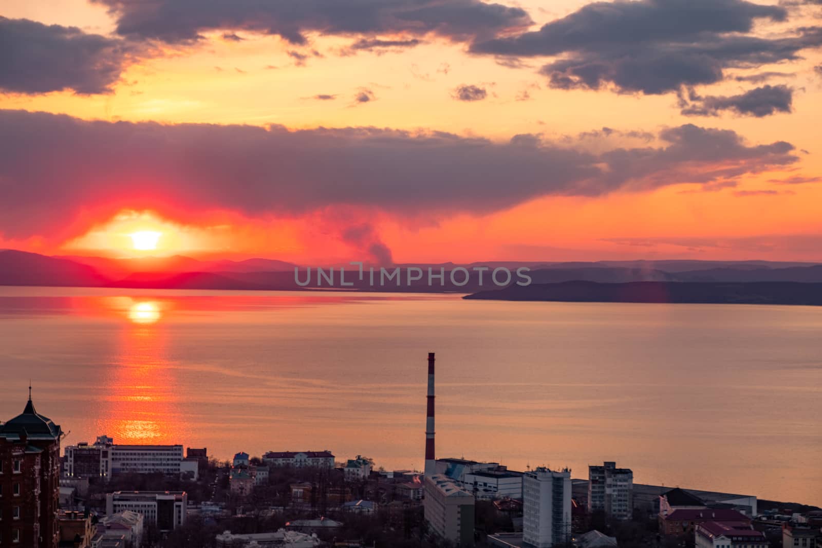 View of the city of Vladivostok from the hill eagle's nest . Sunset. The sky is orange and pink. Sea and city at sunset.