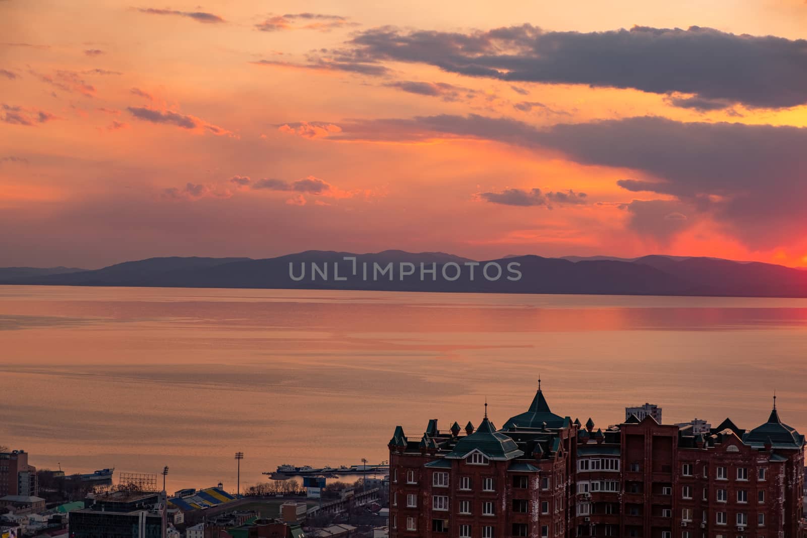 View of the city of Vladivostok from the hill eagle's nest . Sunset. The sky is orange and pink. Sea and city at sunset.