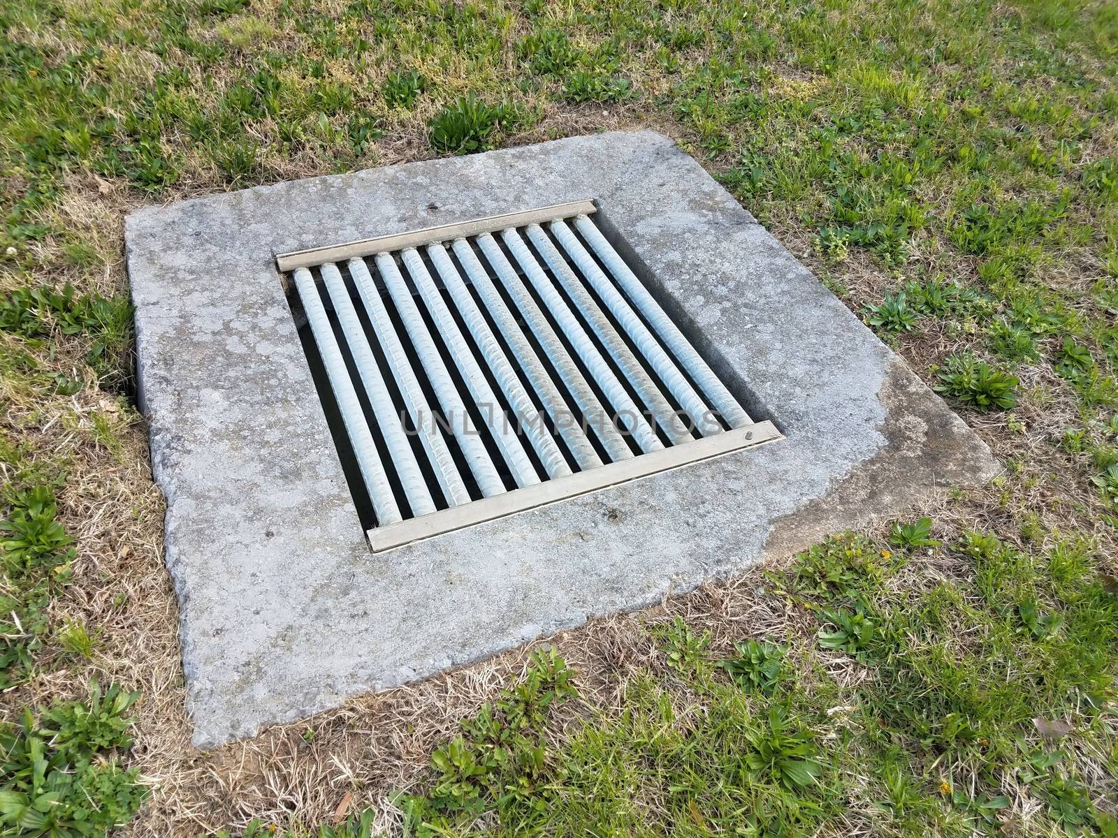 iron metal grate and cement drain and green grass or lawn