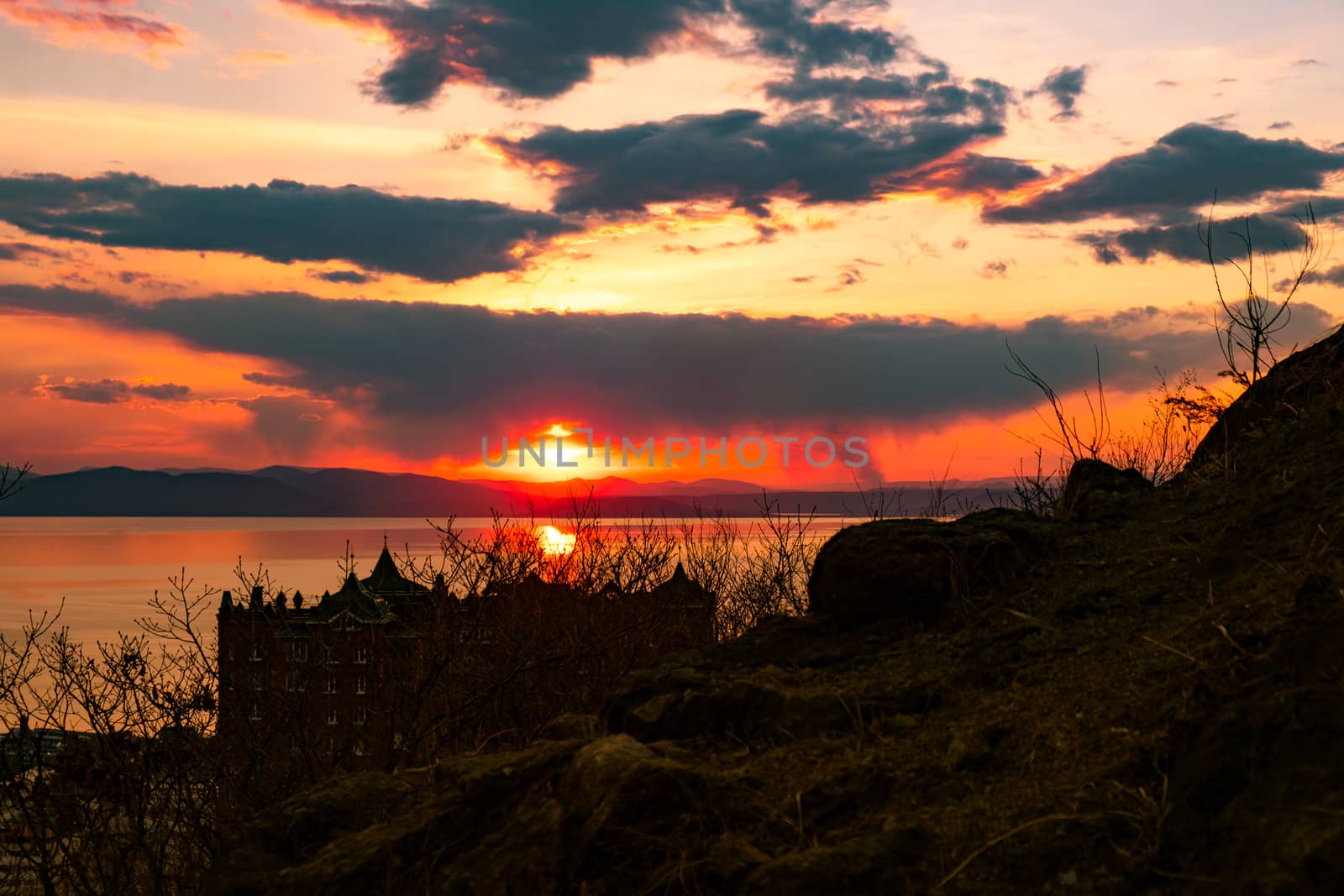 View of the city of Vladivostok from the hill eagle's nest . Sunset. The sky is orange and pink. Sea and city at sunset.