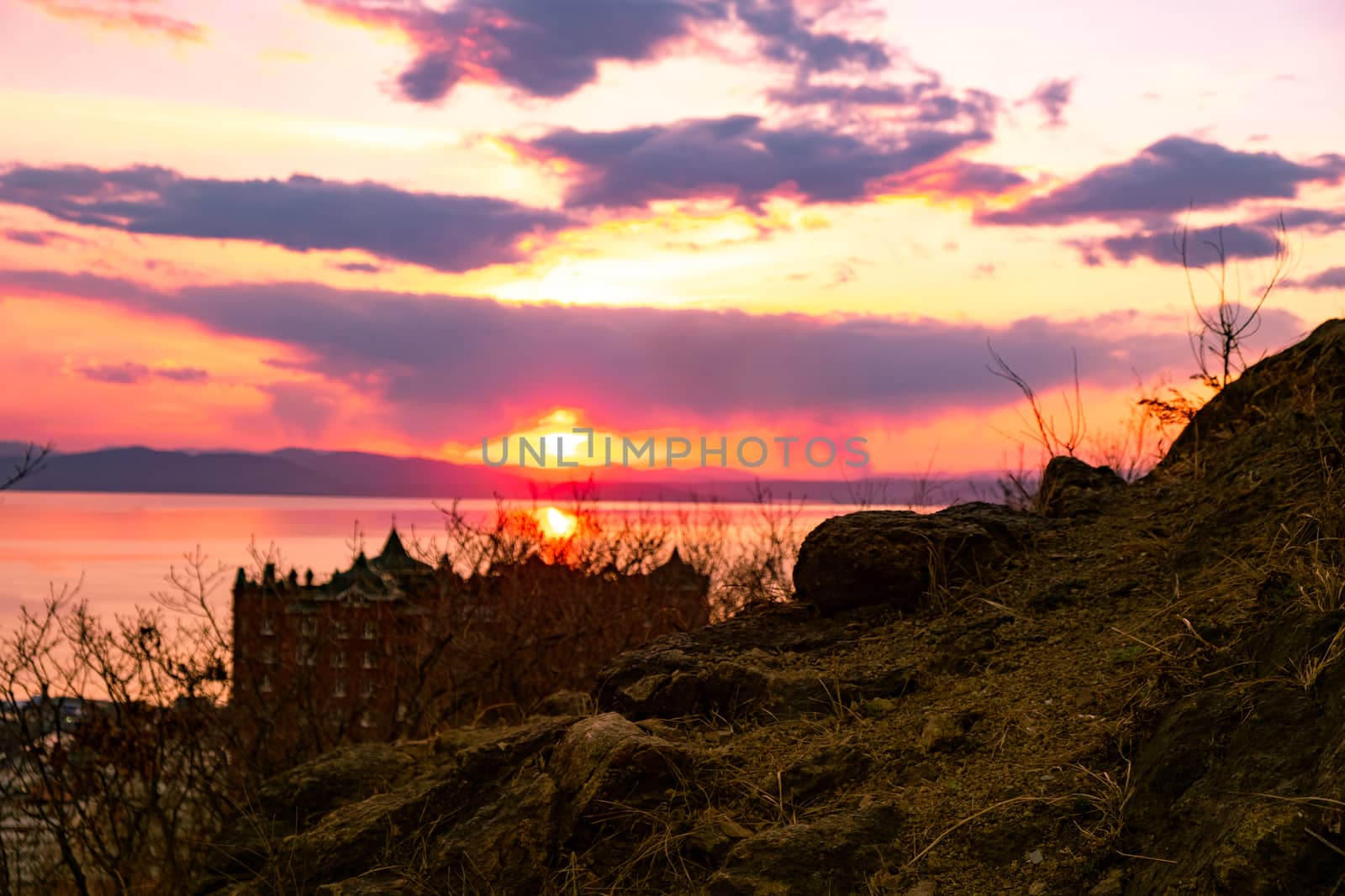 View of the city of Vladivostok from the hill eagle's nest . Sunset. The sky is orange and pink. Sea and city at sunset.