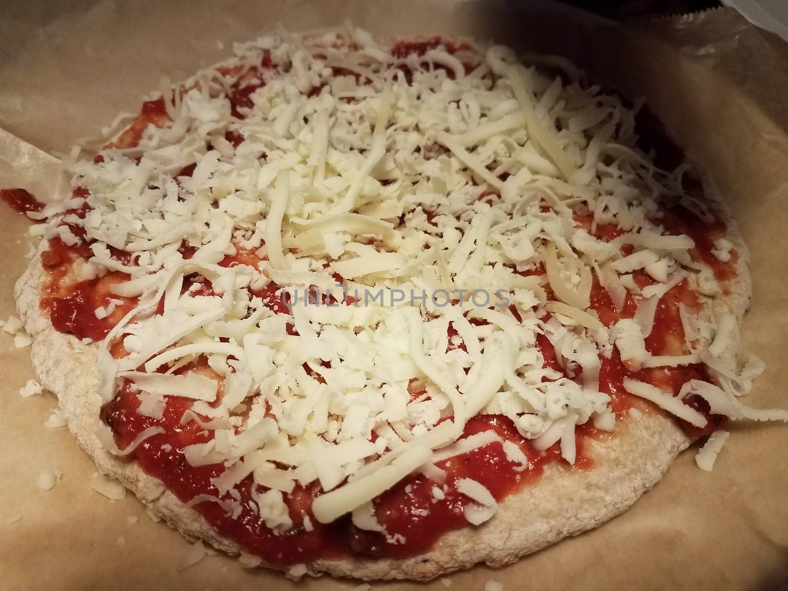 pizza dough and tomato sauce and cheese on wax paper by stockphotofan1