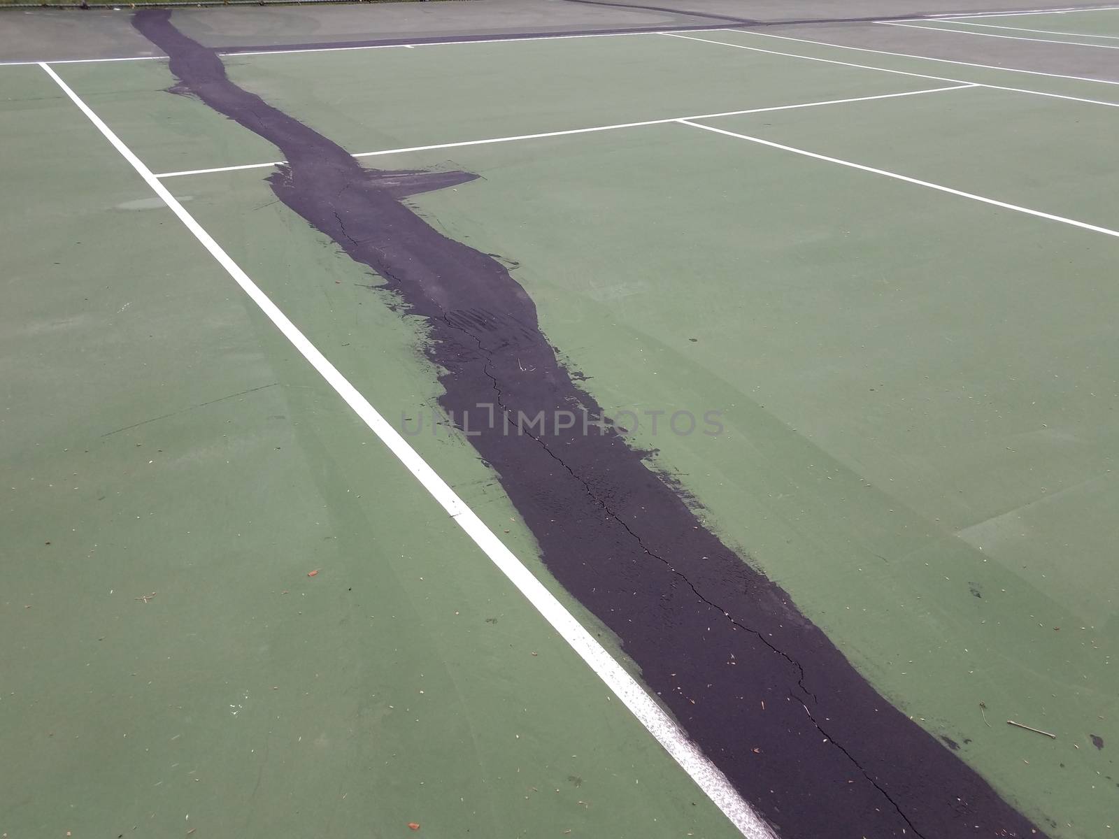 black tar or liquid to repair cracks and damage on green tennis court