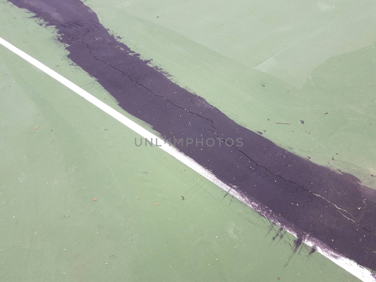 black tar to repair cracks on green tennis court by stockphotofan1
