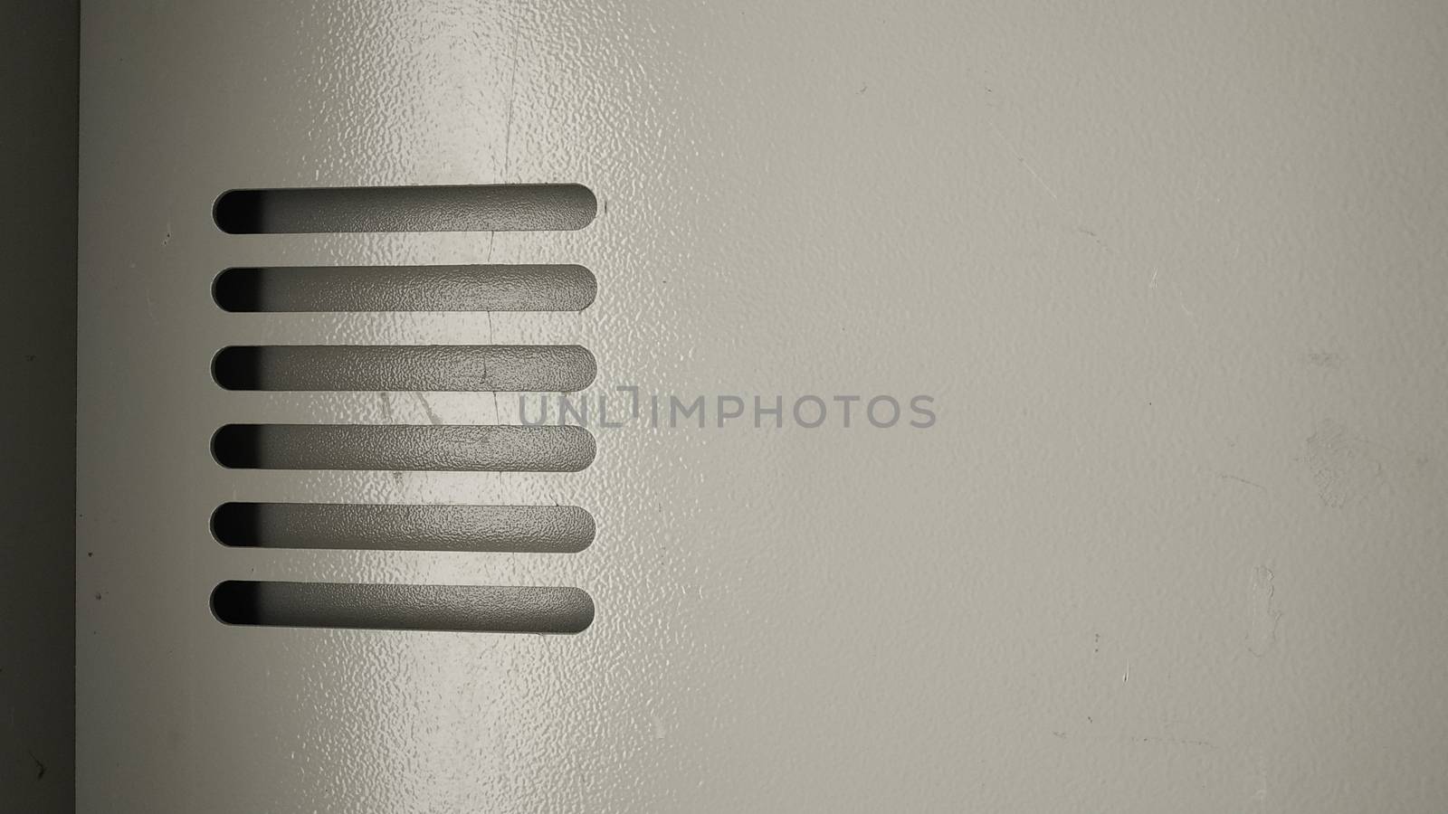 The ventilation grille in the metal wall is painted in a pale beige color. Close-up. by alexey_zheltukhin