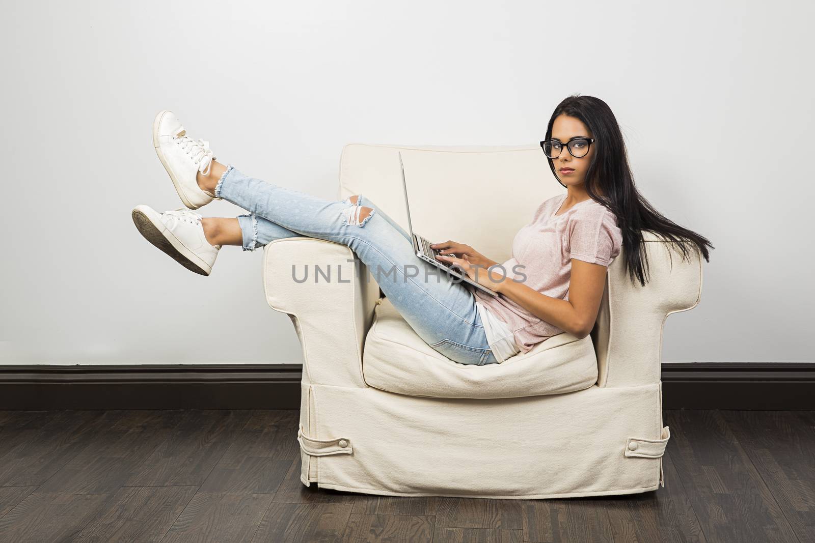 yougn woman with her leg up on a couch, working on a computer