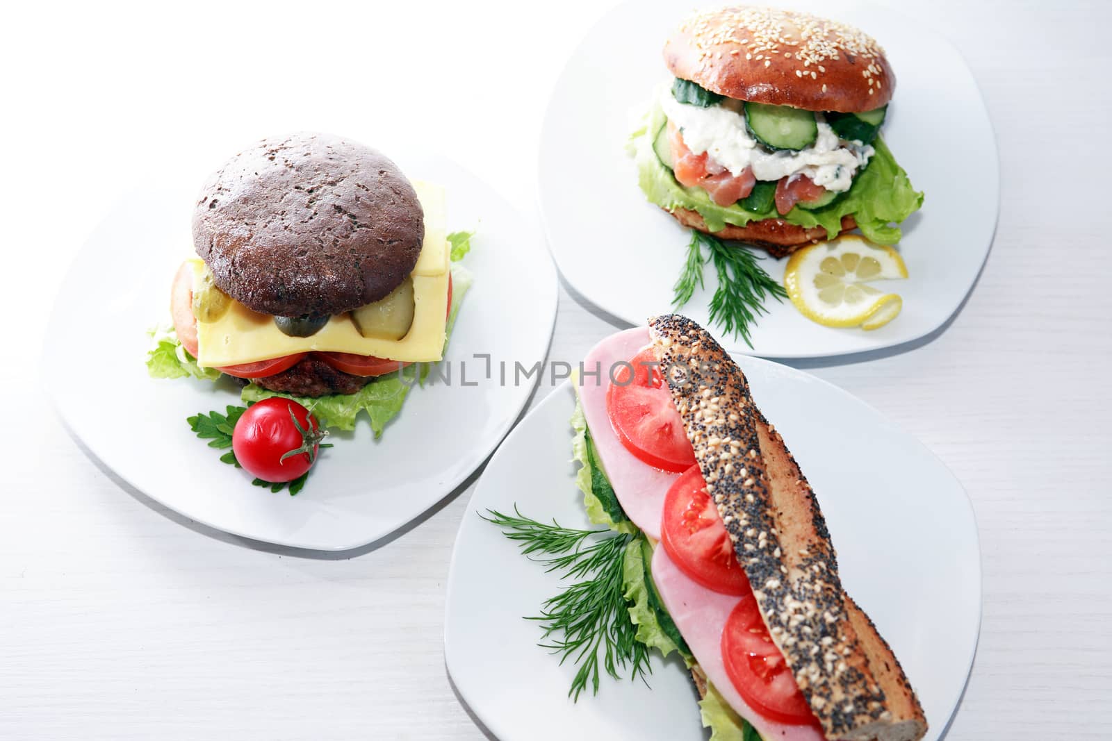 Various sandwiches on plates against white background