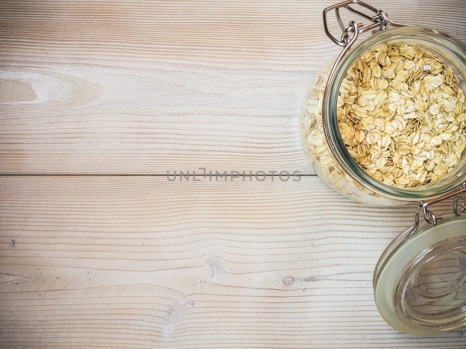 Glass jar with oat-flakes on the wooden background. View from above