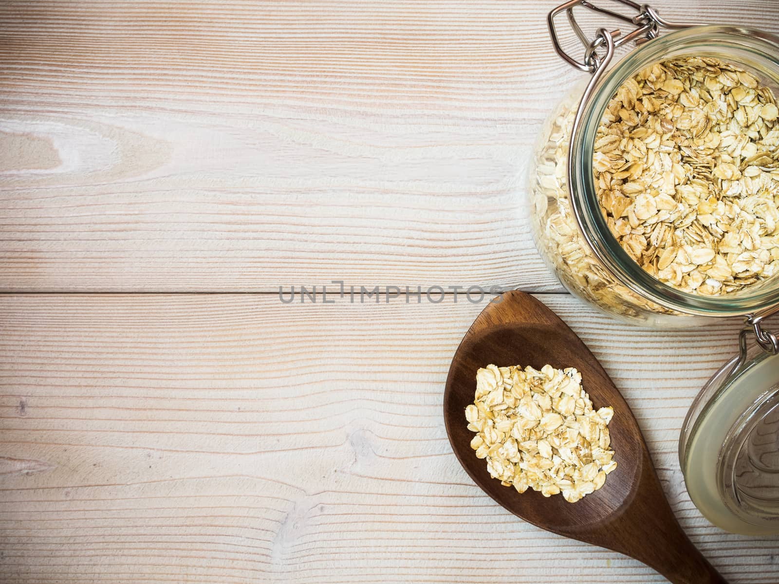 Glass jar with oat-flakes on the wooden background. View from above