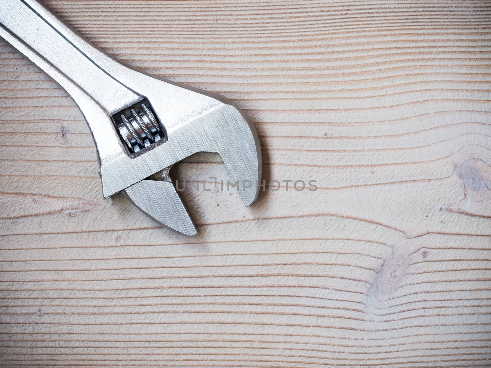 Adjustable wrench on wooden background. Copy space. Construction concept