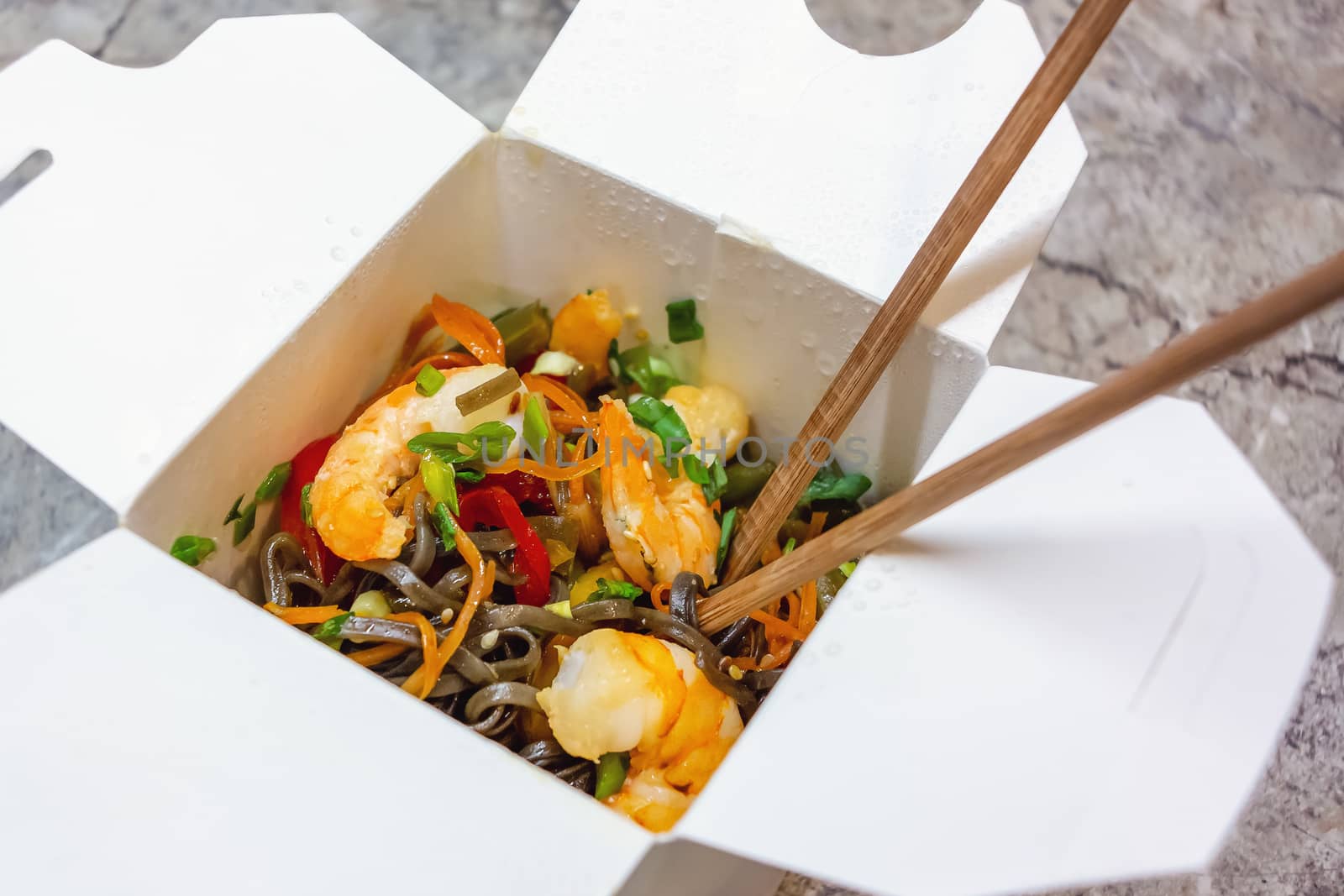Traditional Chinese takeaway fast food - buckwheat soba noodles with vegetables and shrimps packed in a cardboard box with chopsticks close-up - photo, image,