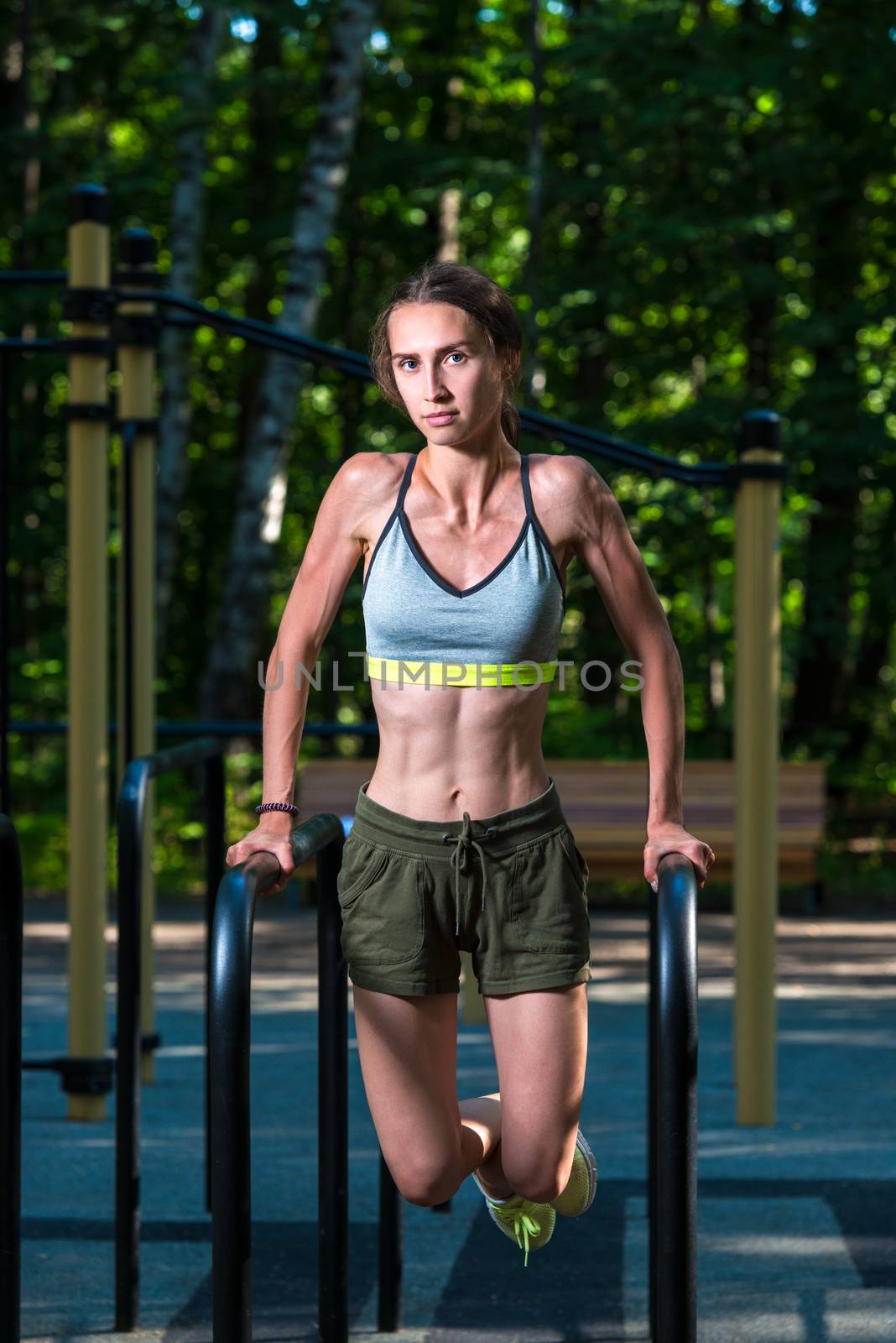 portrait of an athlete who performs exercises for the press outdoors in the park on the simulator