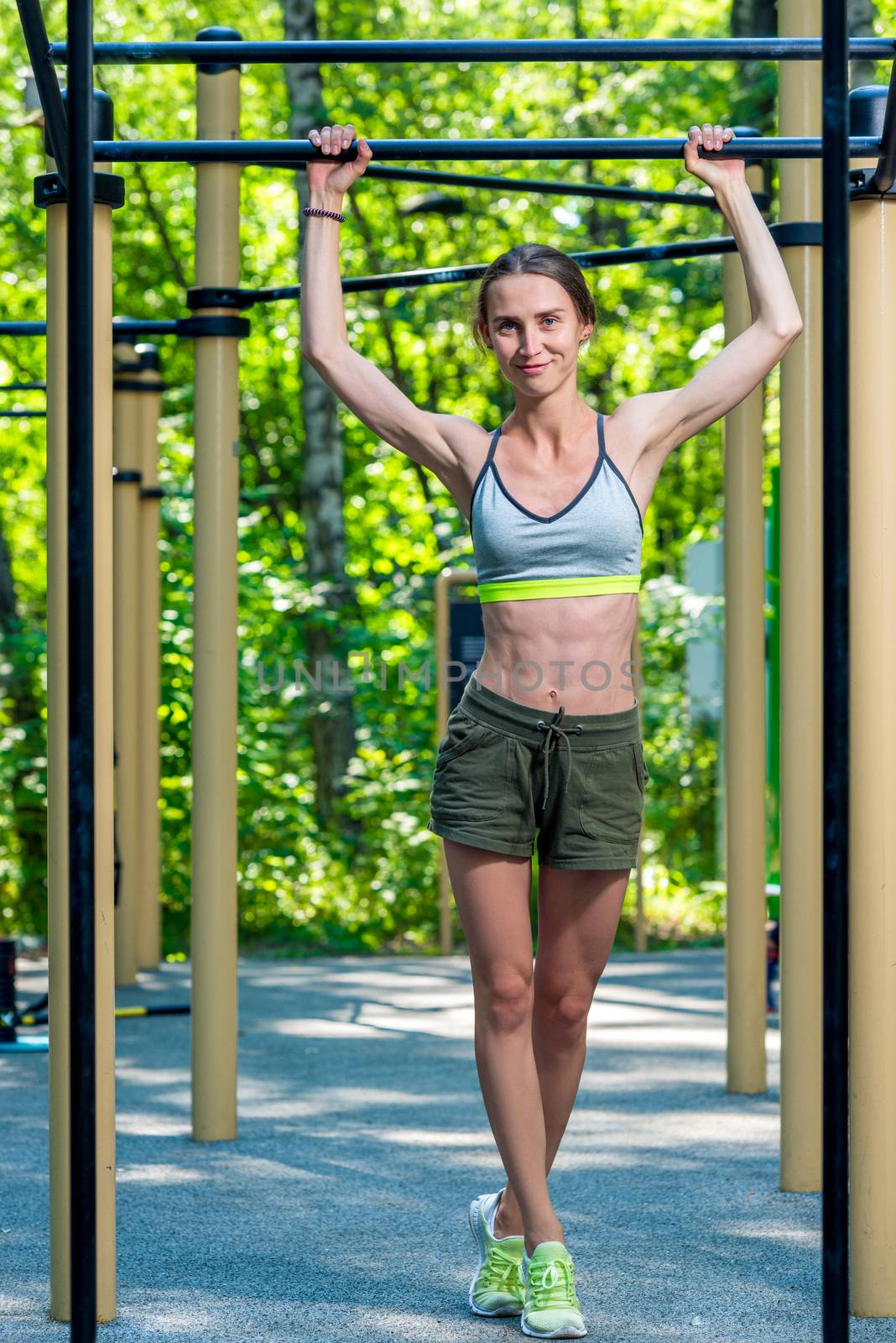 slender muscular woman posing at the gym in the park during training