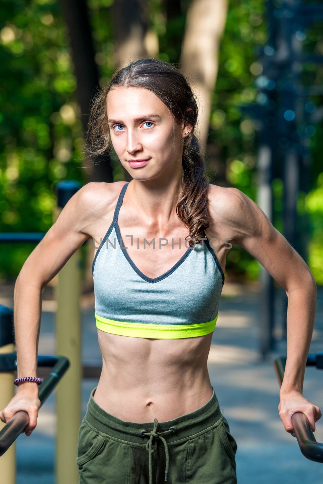vertical portrait of a muscular woman posing at the gym in the park during a workout