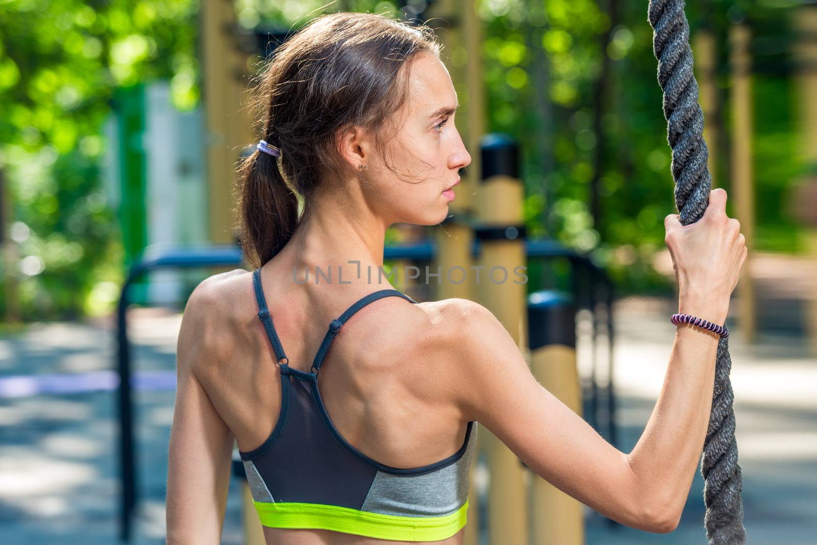 portrait from the back of a sports woman with a rope on the playground, shooting during training