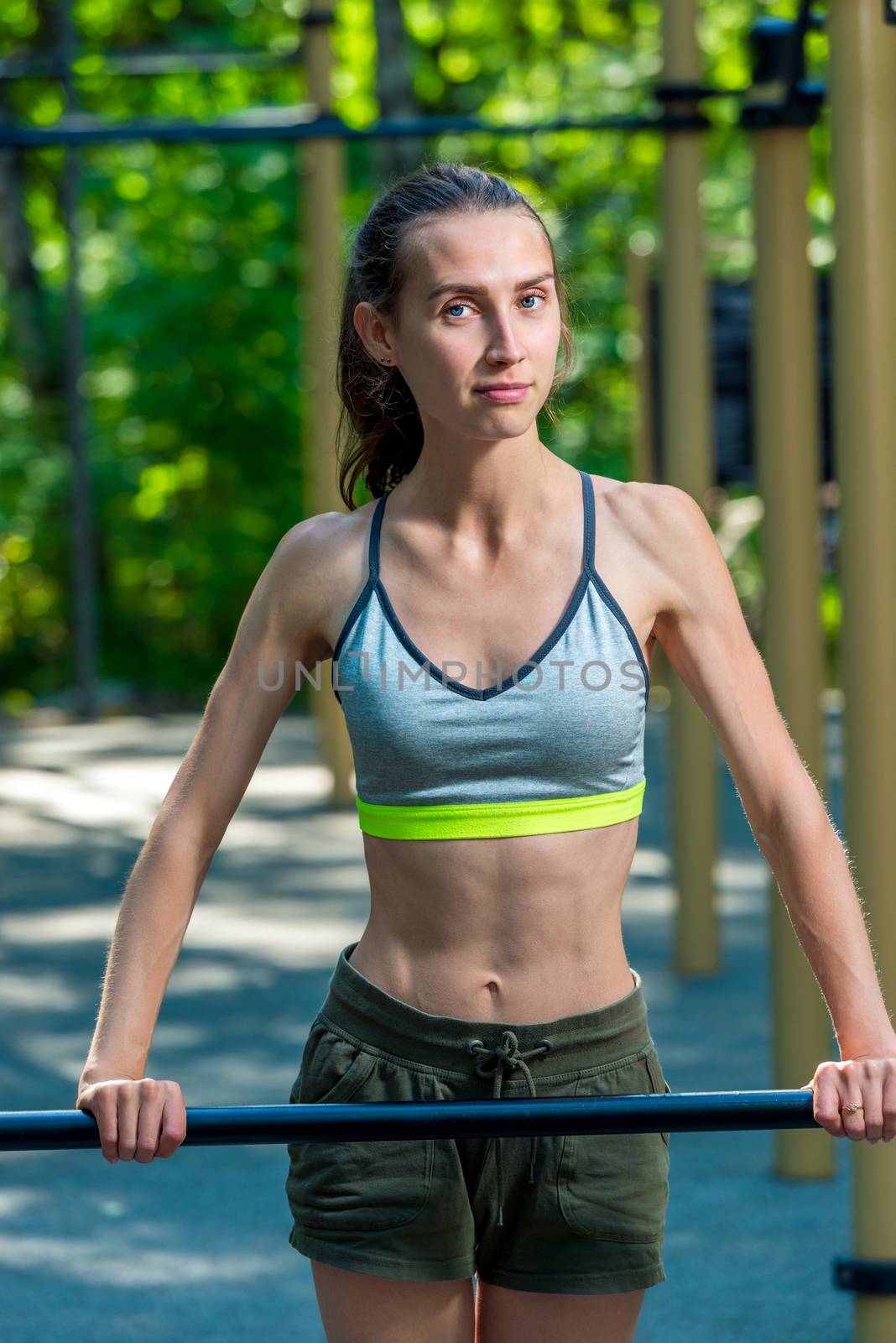 portrait of a slim girl with a sports figure who is engaged on the playground outside in the park