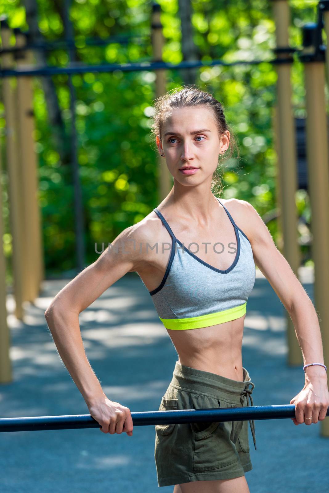 sporty slender woman on fitness equipment on the playground posing
