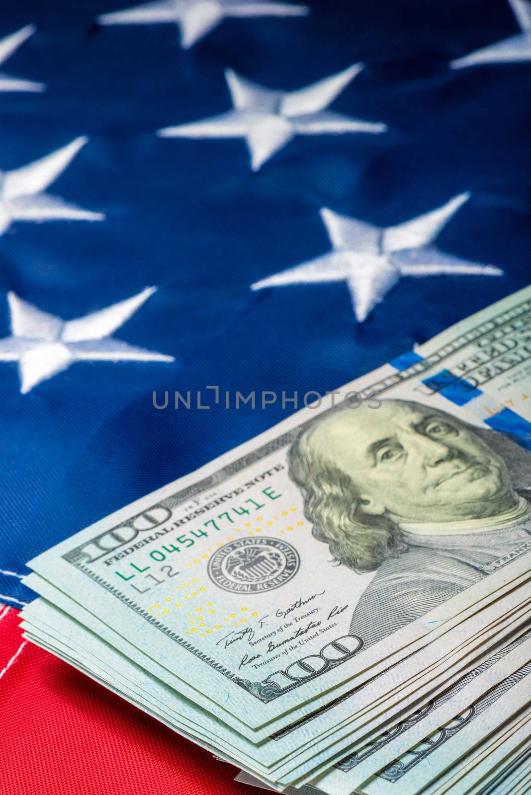 Vertical photo view of a stack of money lying on the flag of the United States of America close-up
