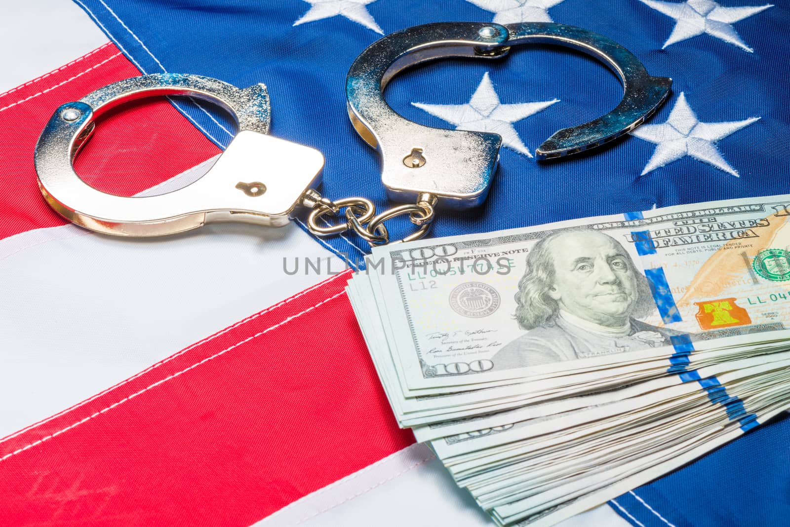 Concept photo of a pile of money and handcuffs on the American flag close up