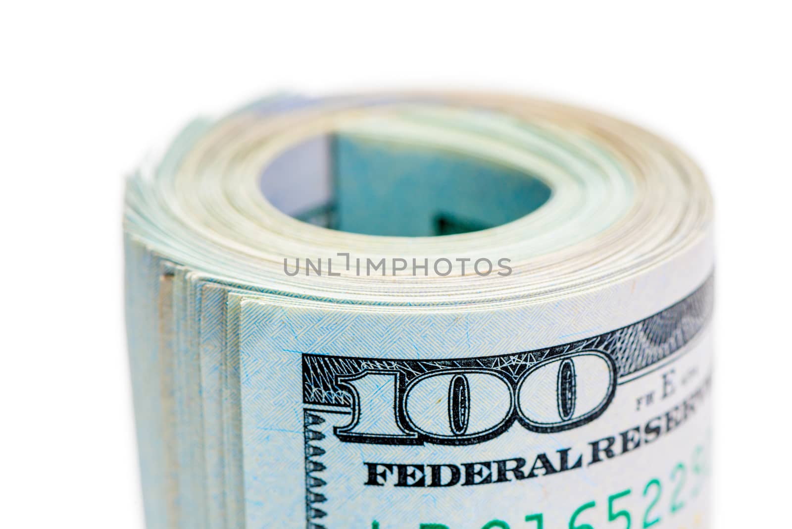 Macro roll of rolled up 100 dollar bills and tightened by rubber band on white background isolated