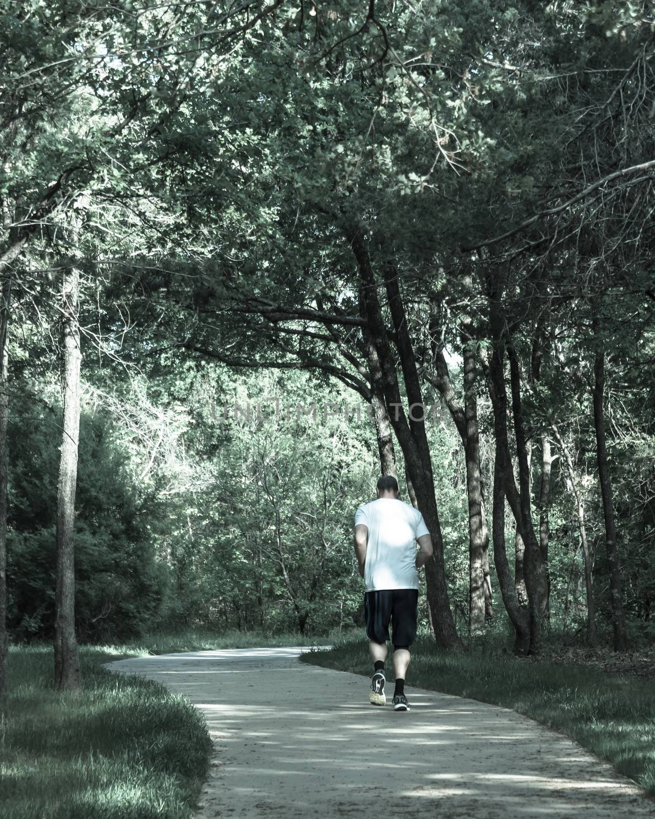 Healthy man running in the s-curved pathway in park near Dallas, by trongnguyen