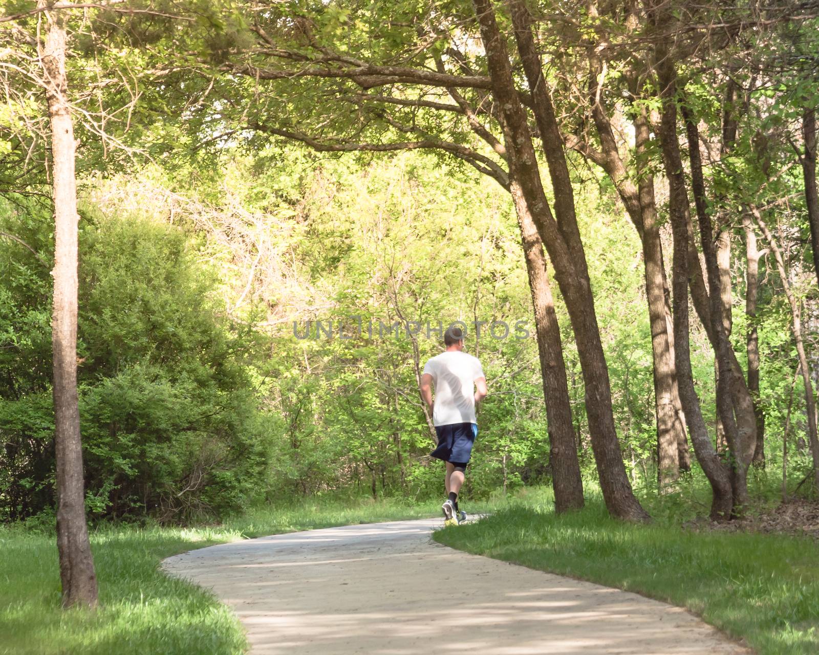 Back view of healthy man running in the park near Dallas, Texas by trongnguyen