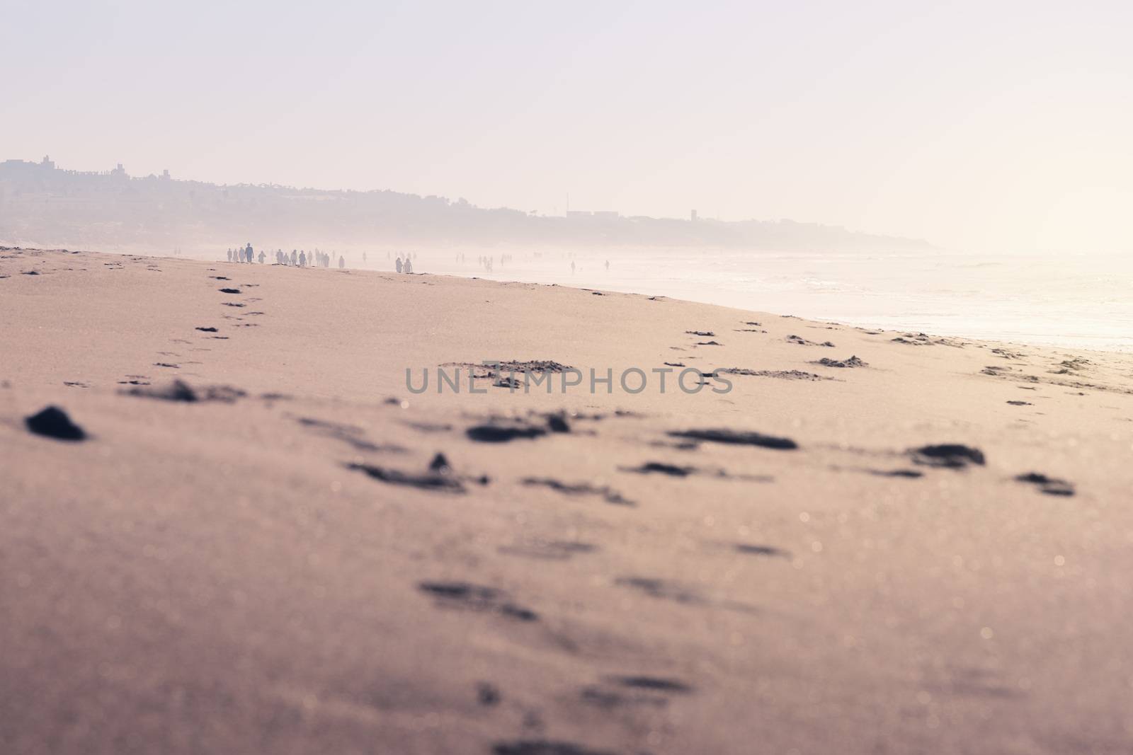 traces of people walking in the sand of the beach, the landscape is covered by fog