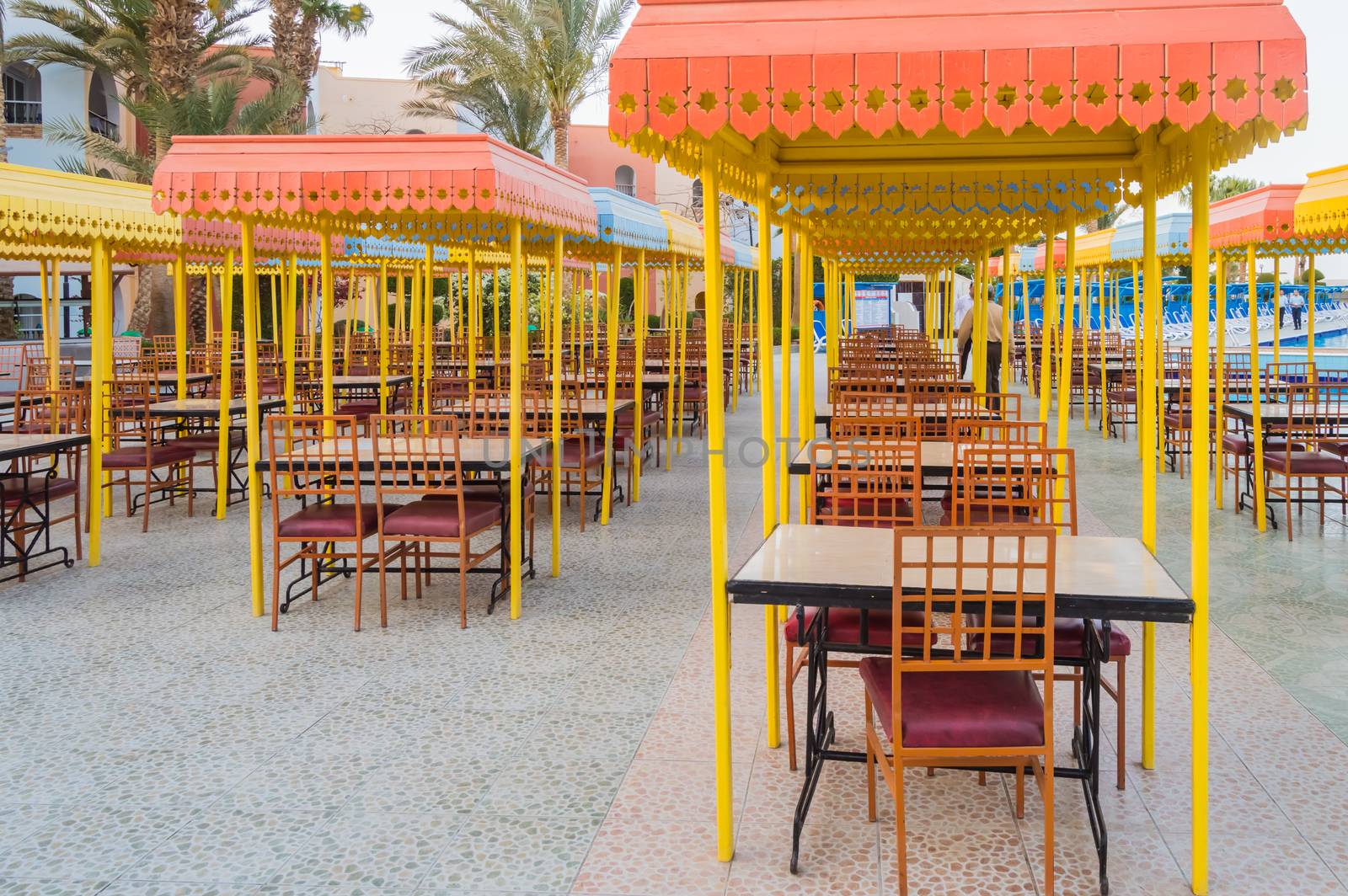 Outdoor wooden restaurant terrace with tables with four seats with a small roof against the sun.