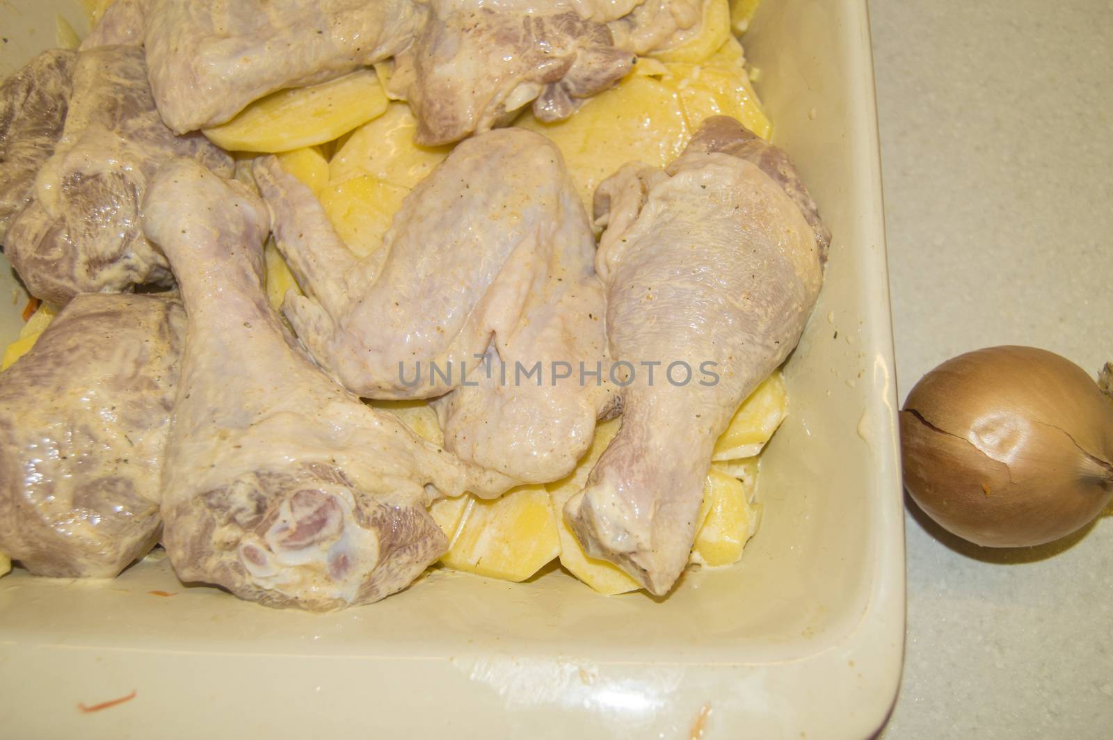 Pieces of raw chicken and sliced potatoes, marinated with mayonnaise and laid out in ceramic baking dish. Cooking holiday food for Christmas, Easter, Thanksgiving. concept of a family holiday dinner