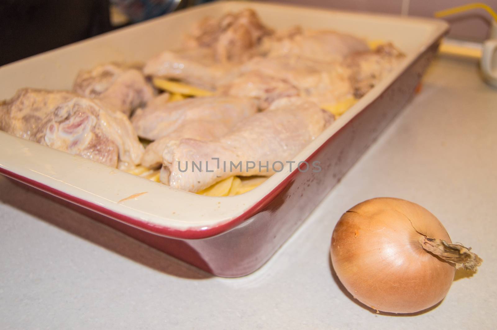 Pieces of raw chicken and sliced potatoes, marinated with mayonnaise and laid out in ceramic baking dish. Cooking holiday food for Christmas, Easter, Thanksgiving. concept of a family holiday dinner