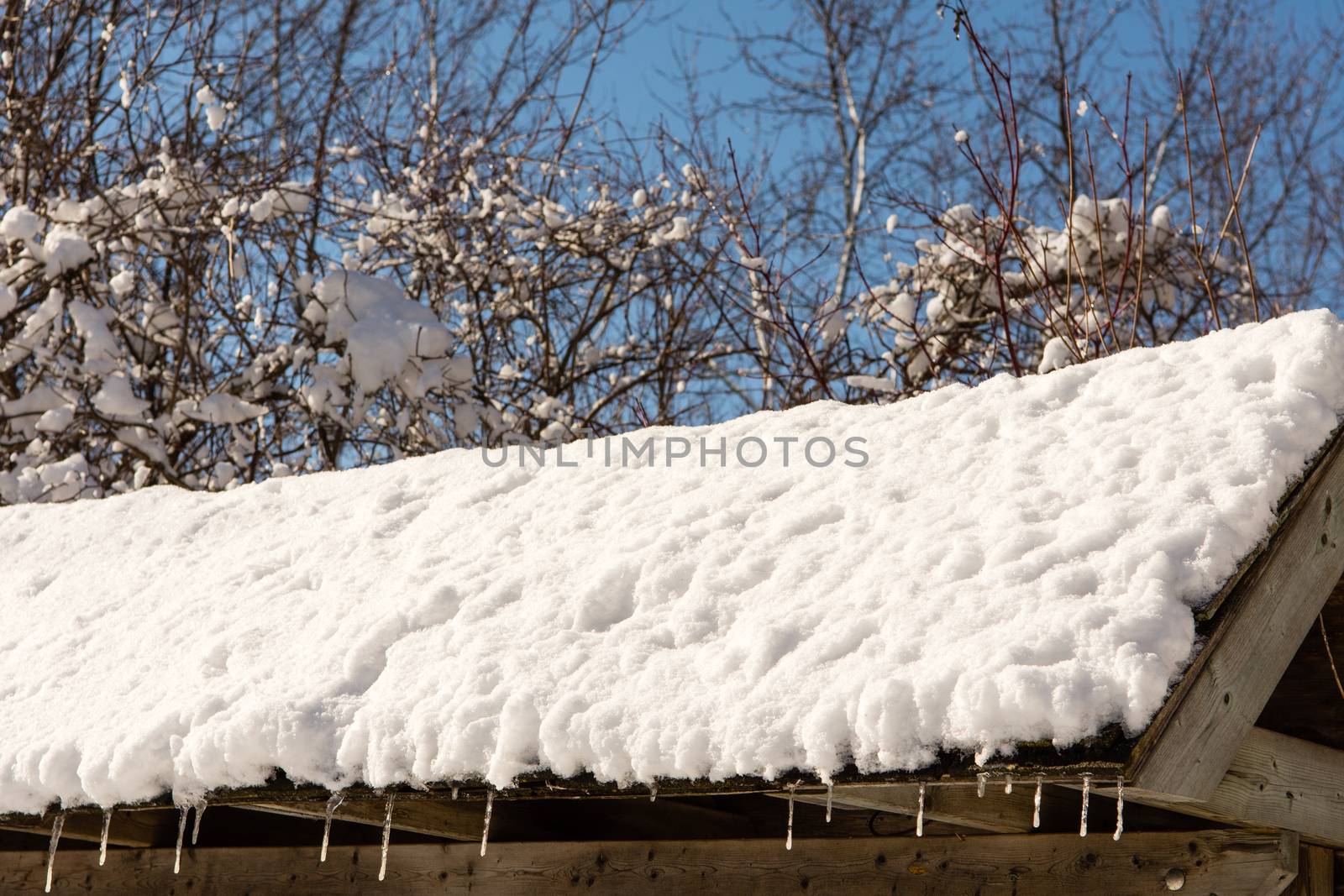 Fragment of a snow covered roof with hanging icicles