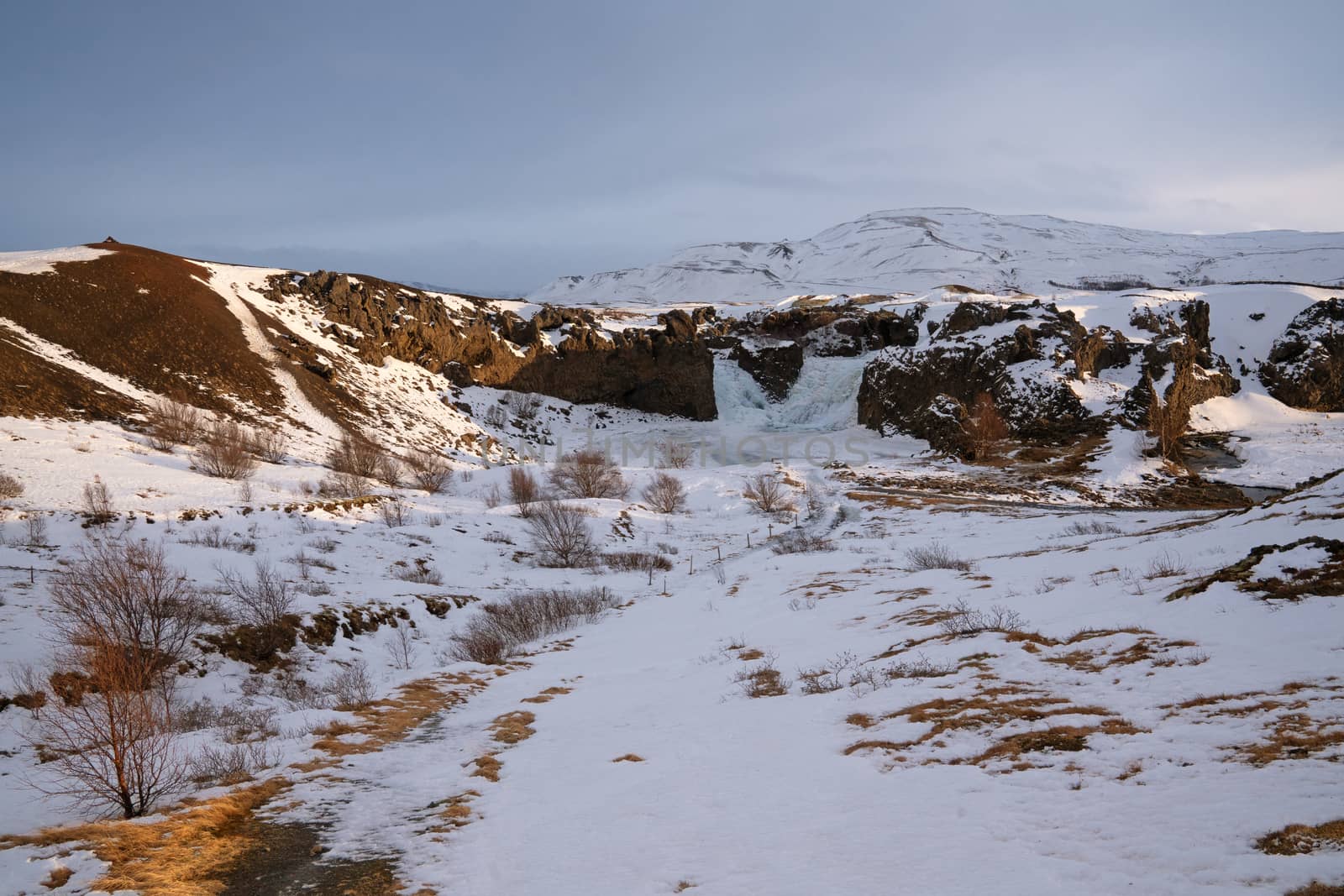 Frozen Hjalparfoss waterfall on a cloudy morning, winter in Iceland, Europe