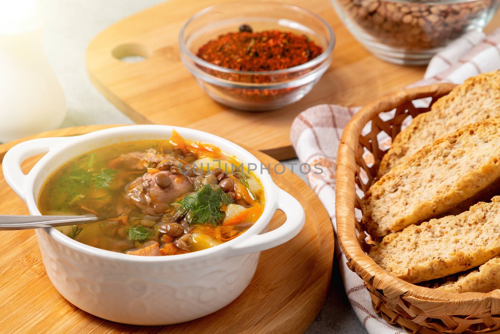 Lentil soup with chicken in a white bowl on a wooden board by galsand