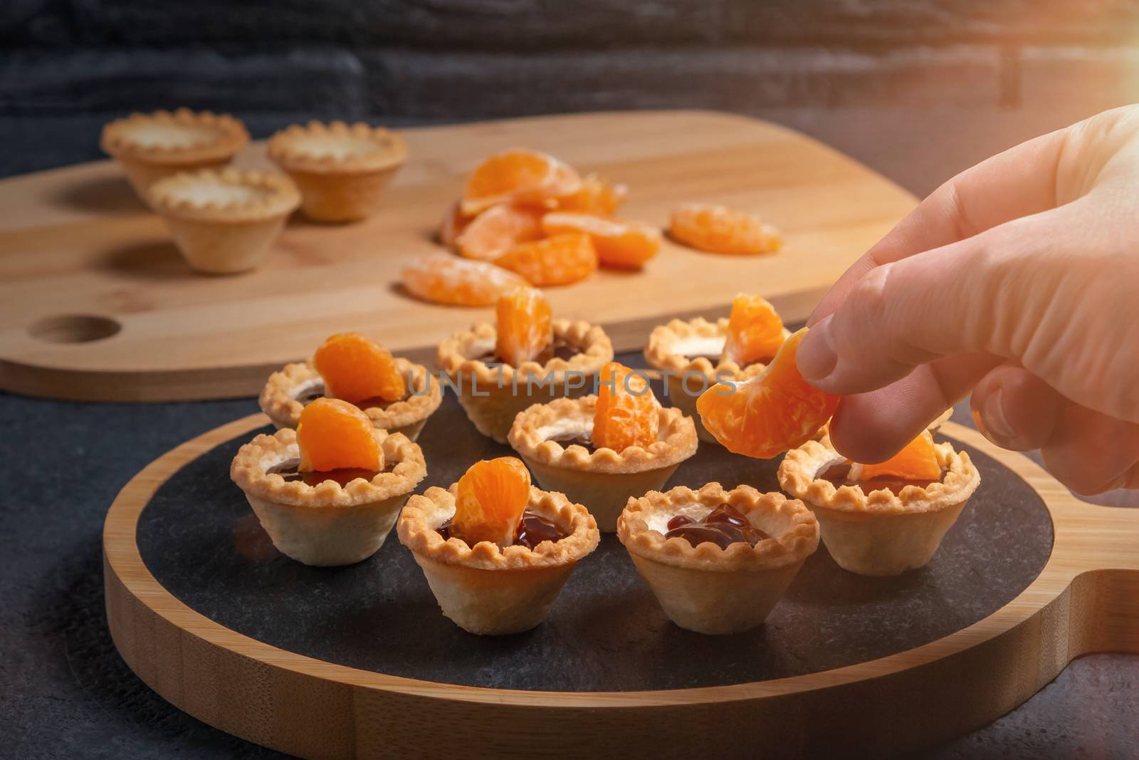 Cooking sweet tartlets with slices of tangerine and chocolate - unfolding tangerine slices by galsand