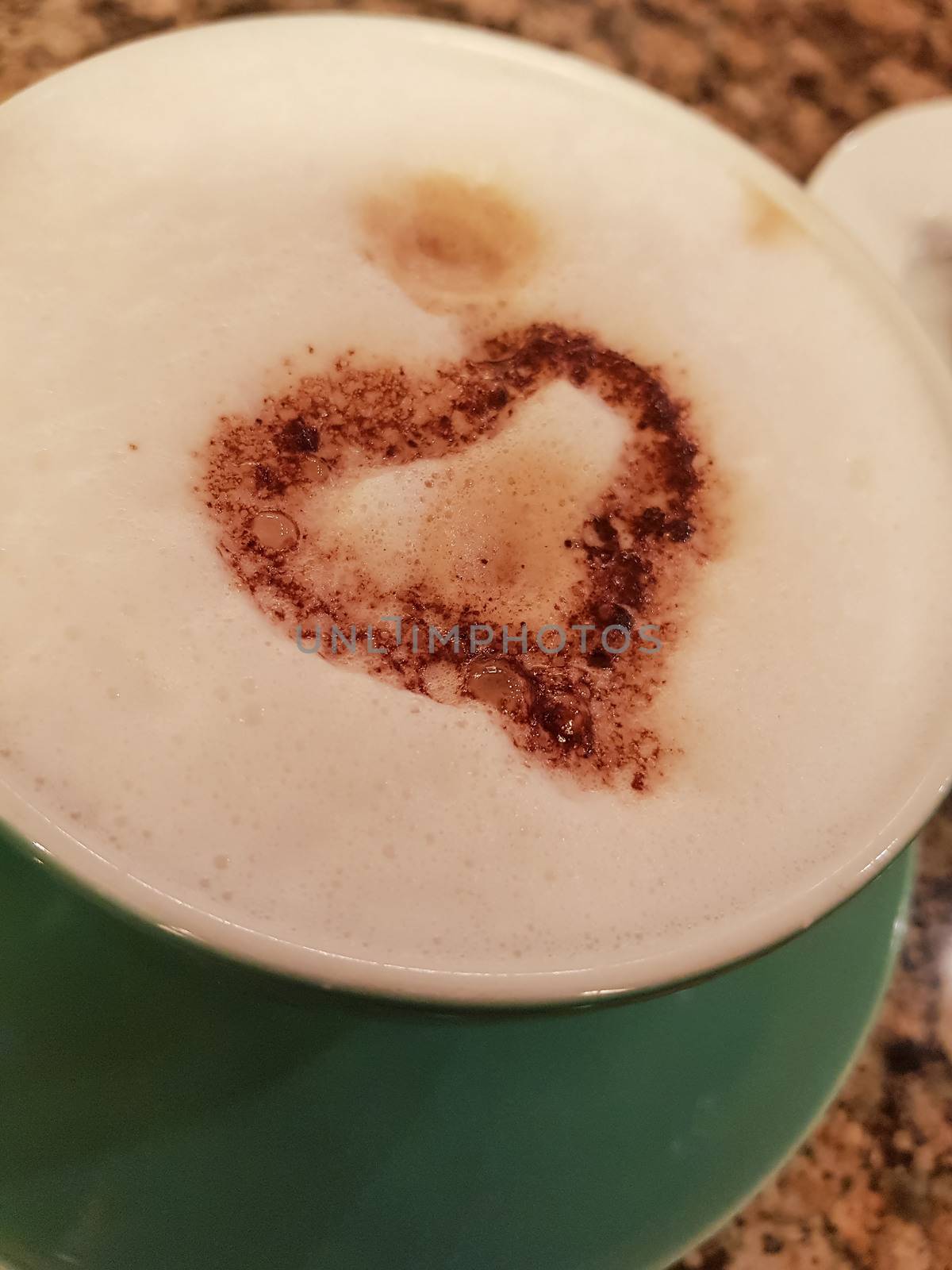 Green cup of coffee with foam and heart