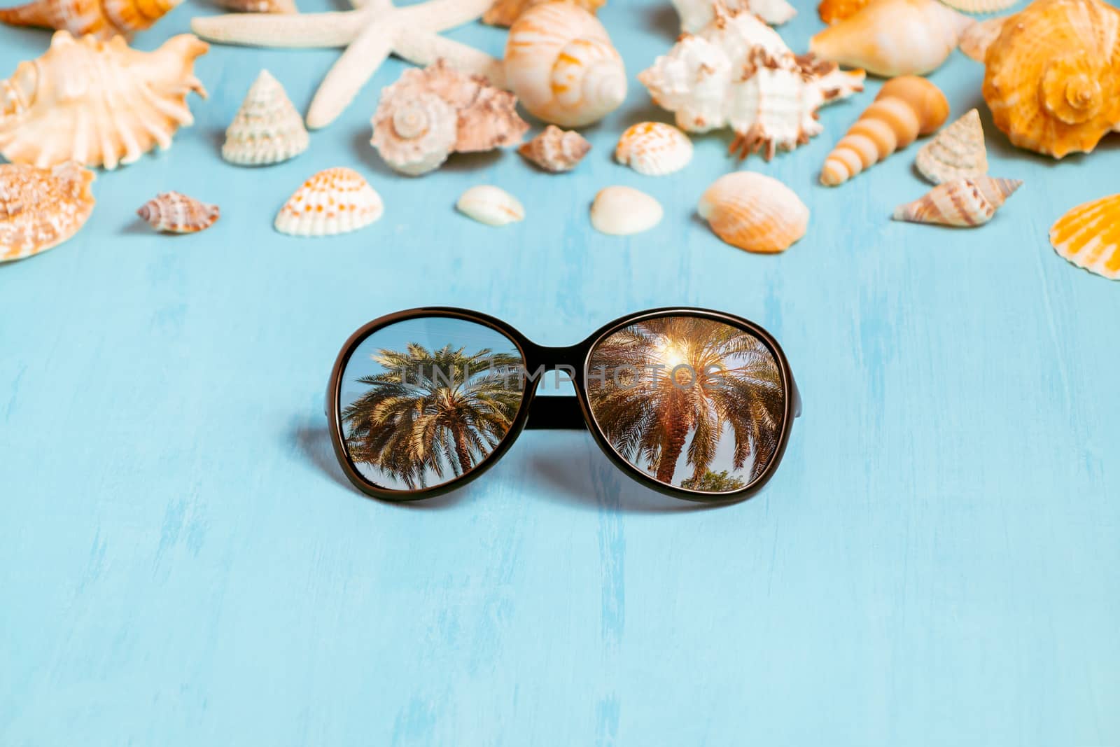Blue sea background with sunglasses and seashells, summer holiday and vacation time concept by galsand