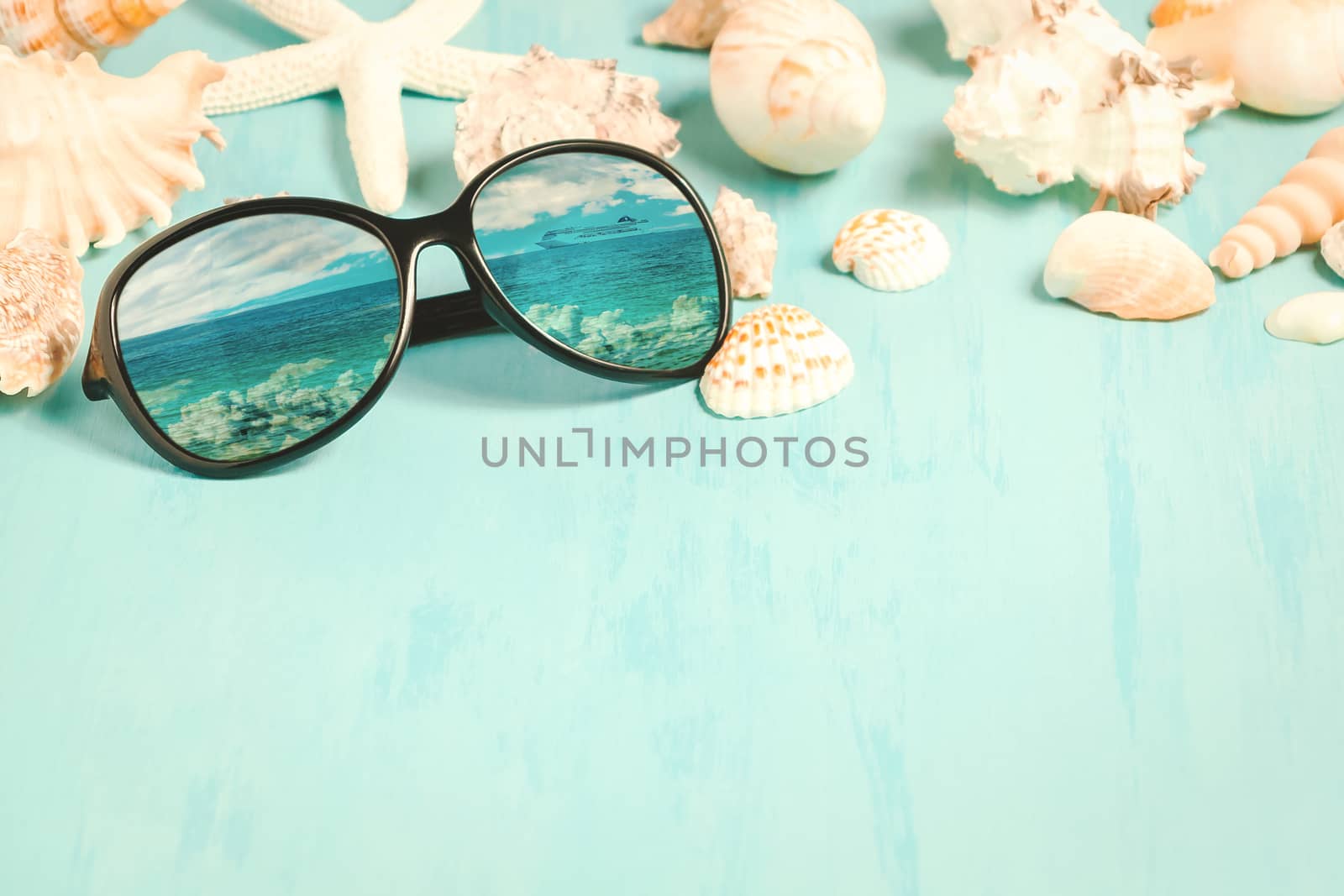 Blue sea background with sunglasses and seashells, summer holiday and vacation time concept.