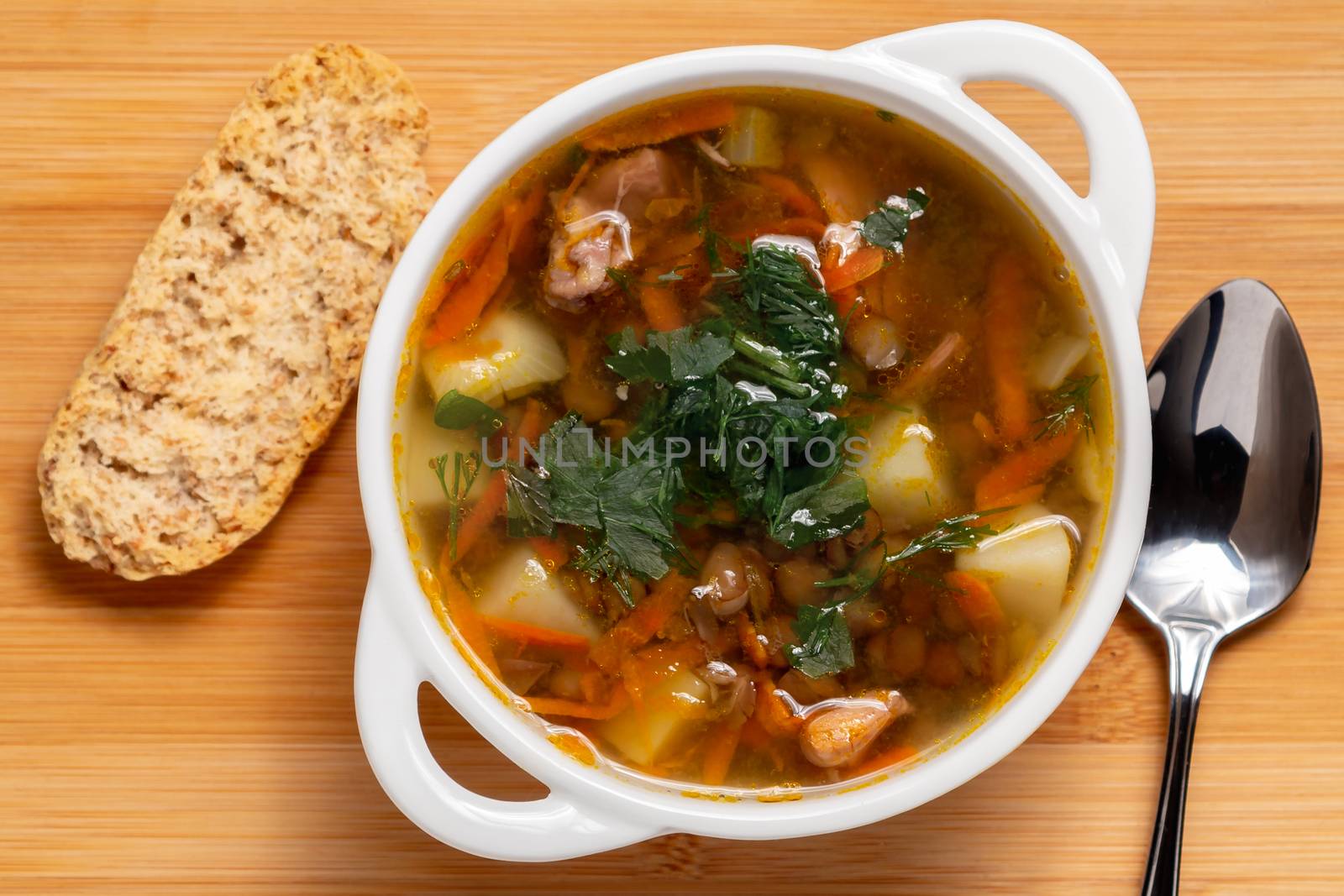 Lentil soup with chicken in a white bowl on a wooden board, top view by galsand