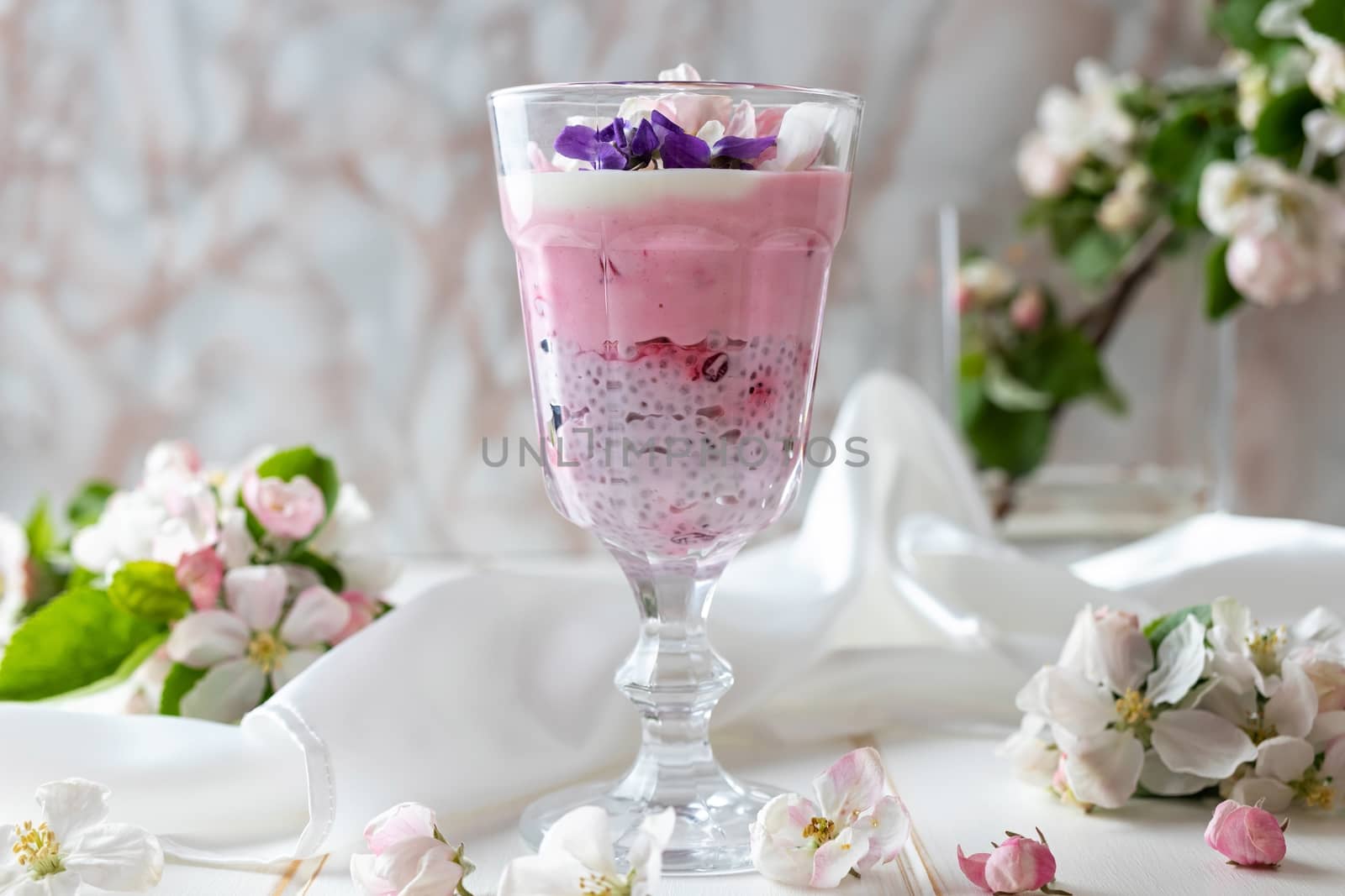 Layered chia pudding with yogurt, red currants and apple blossoms