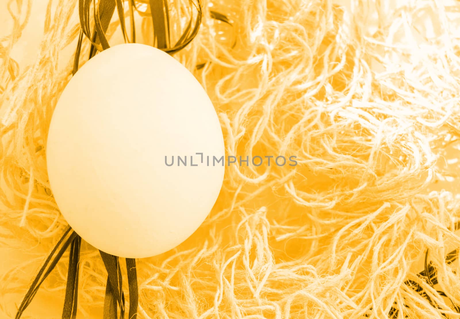 Easter white egg on gold braided nest background, top view, flat, copy space, bright light