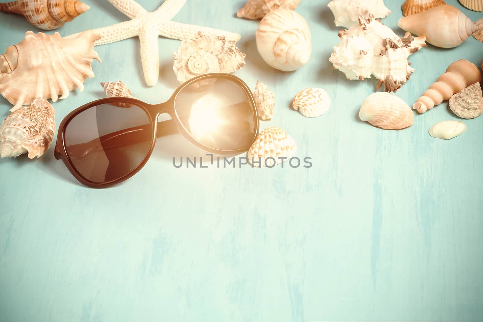 Blue sea background with sunglasses and seashells, summer holiday and vacation time concept.