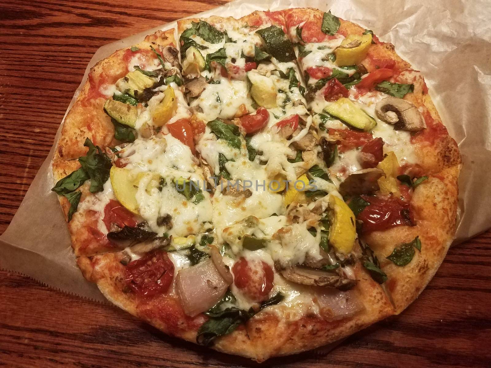 vegetable pizza with cheese and wax paper on wood table