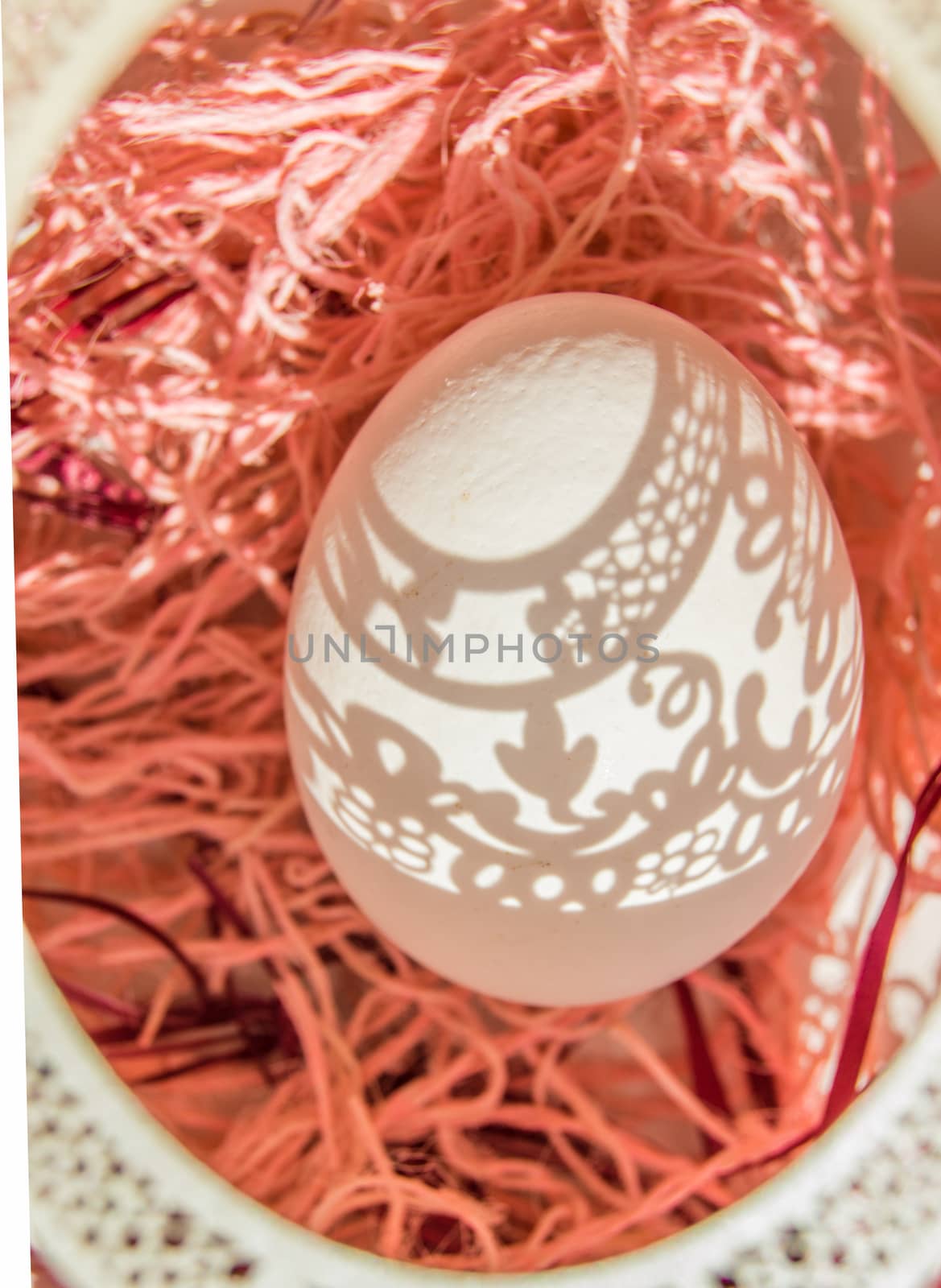 Easter. A beautiful Easter card with an openwork vertical oval frame through which beautiful shadows fall on a white egg. Green background, top view.