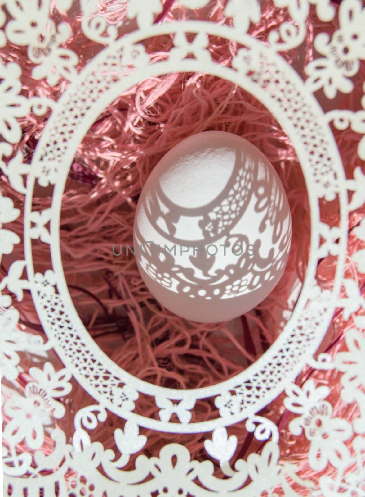 Easter. A beautiful Easter card with an openwork vertical oval frame through which beautiful shadows fall on a white egg. Green background, top view by claire_lucia