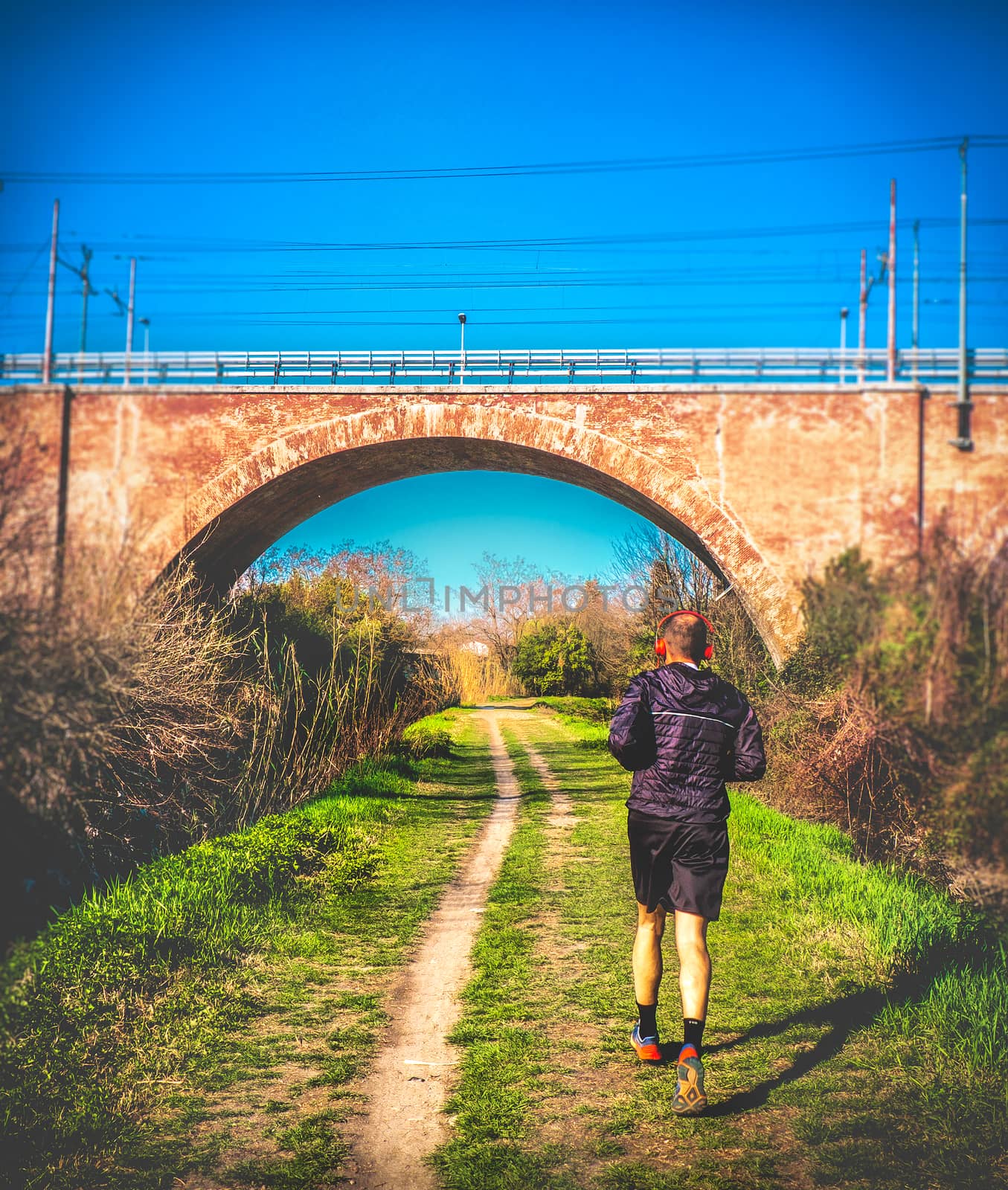 individual jogging marathon in urban park uber the bridge vertical by LucaLorenzelli