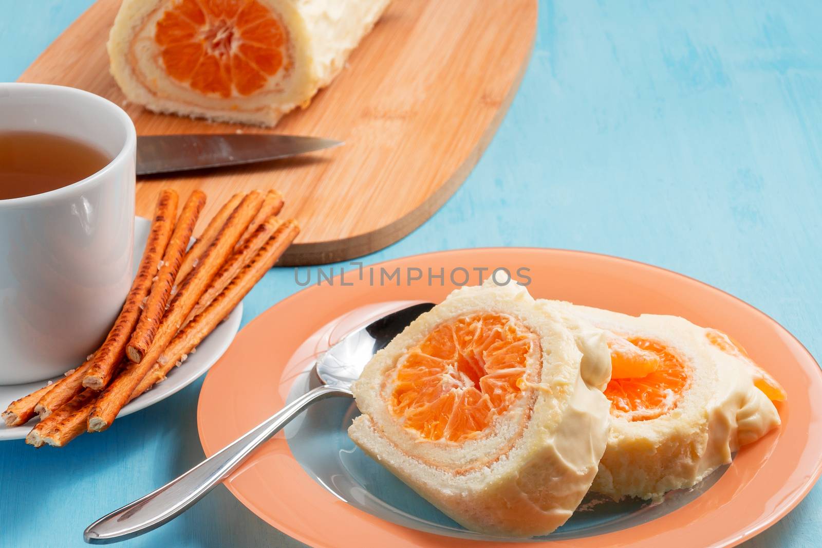 Sweet roll with whipped cream and tangerine filling and a cup of tea by galsand