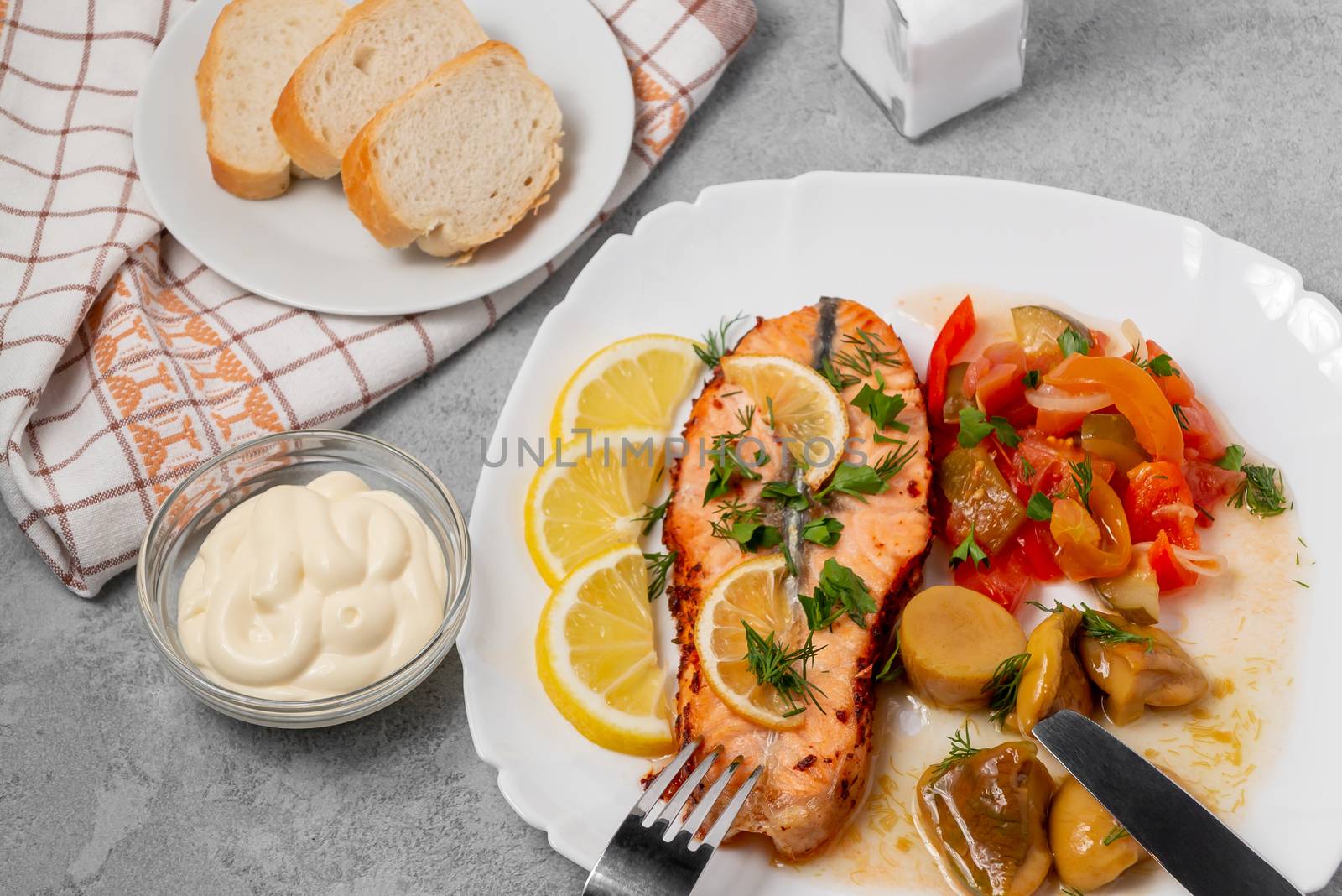 Baked salmon fillet medallion with salad of pickled vegetables and mushrooms on a white plate on a gray background, top view, flatlay by galsand